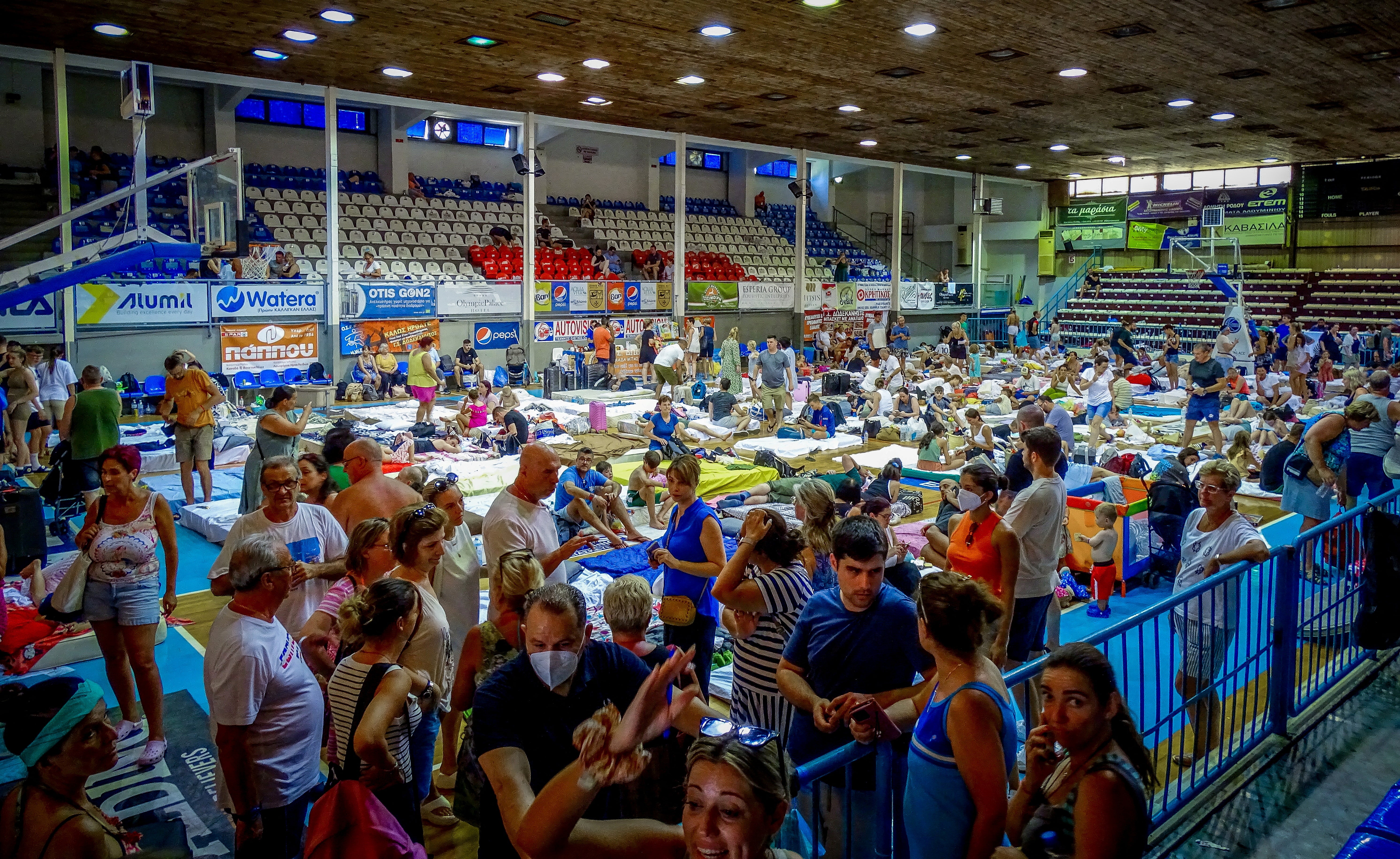 Tourists are sheltered in a stadium after being evacuated following a wildfire on the island of Rhodes