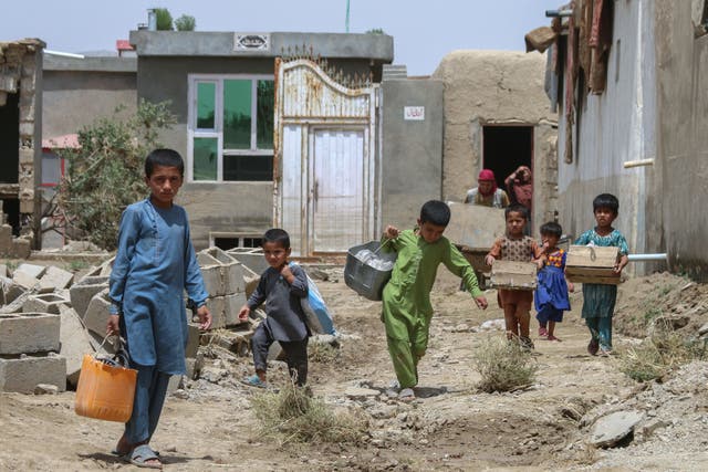 <p>Afghan children carry their belongings following flash floods in the Khair Abad area in Ghazni province</p>