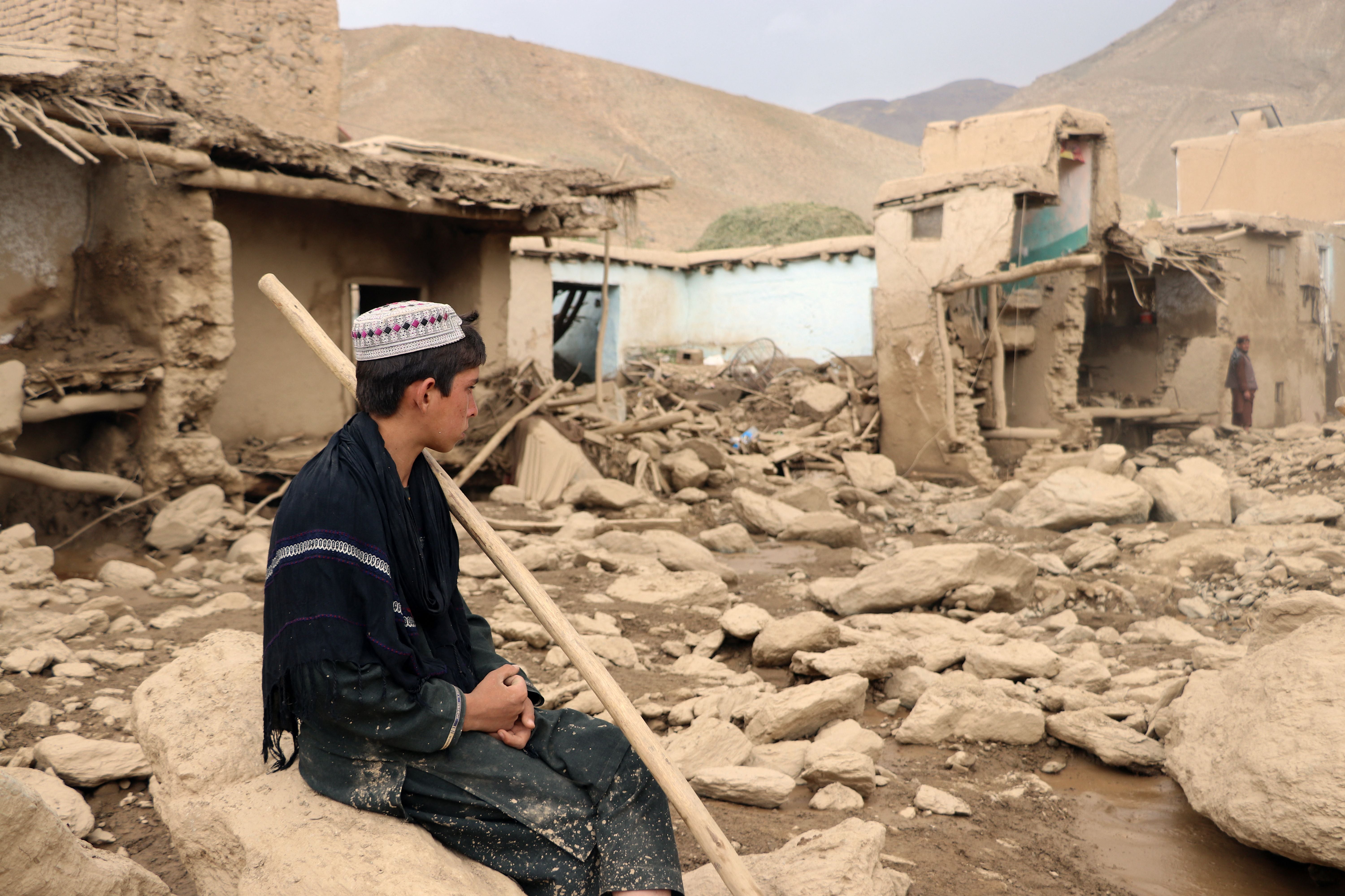 An Afghan resident sits next to his house that was damaged in flash floods in the Jalrez district of Maidan Wardak province