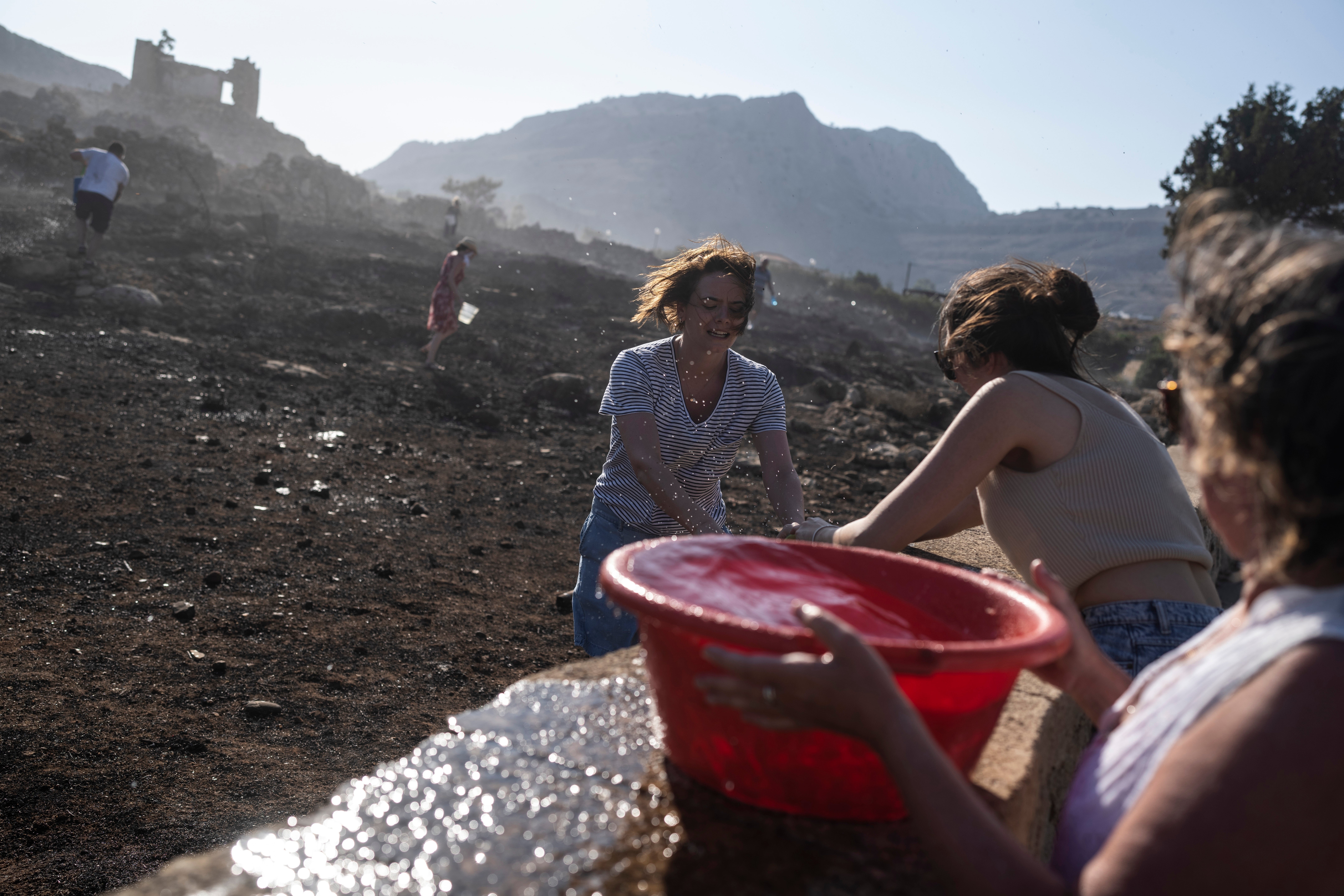German tourists together with local residents try to extinguish a fire near the seaside resort of Lindos