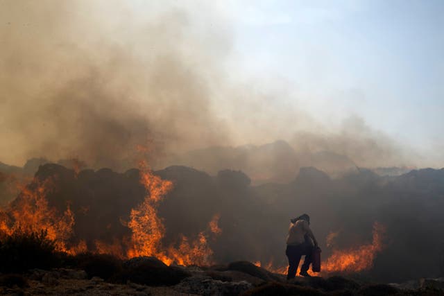 A man tries to extinguish a fire, near the seaside resort of Lindos on the island of Rhodes (Petros Giannakouris/AP/PA)