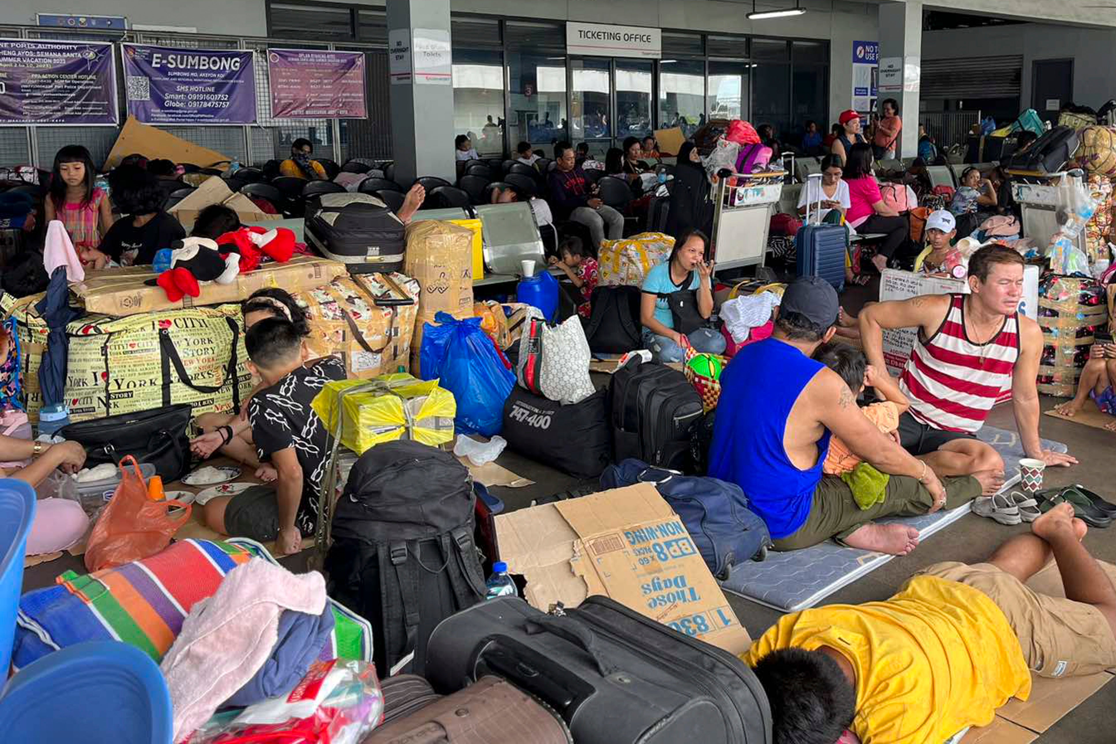 In this photo provided by the Philippine Coast Guard, stranded passengers stay at a passenger terminal after sea travel was suspended due to Typhoon Doksuri in Manila, Philippines