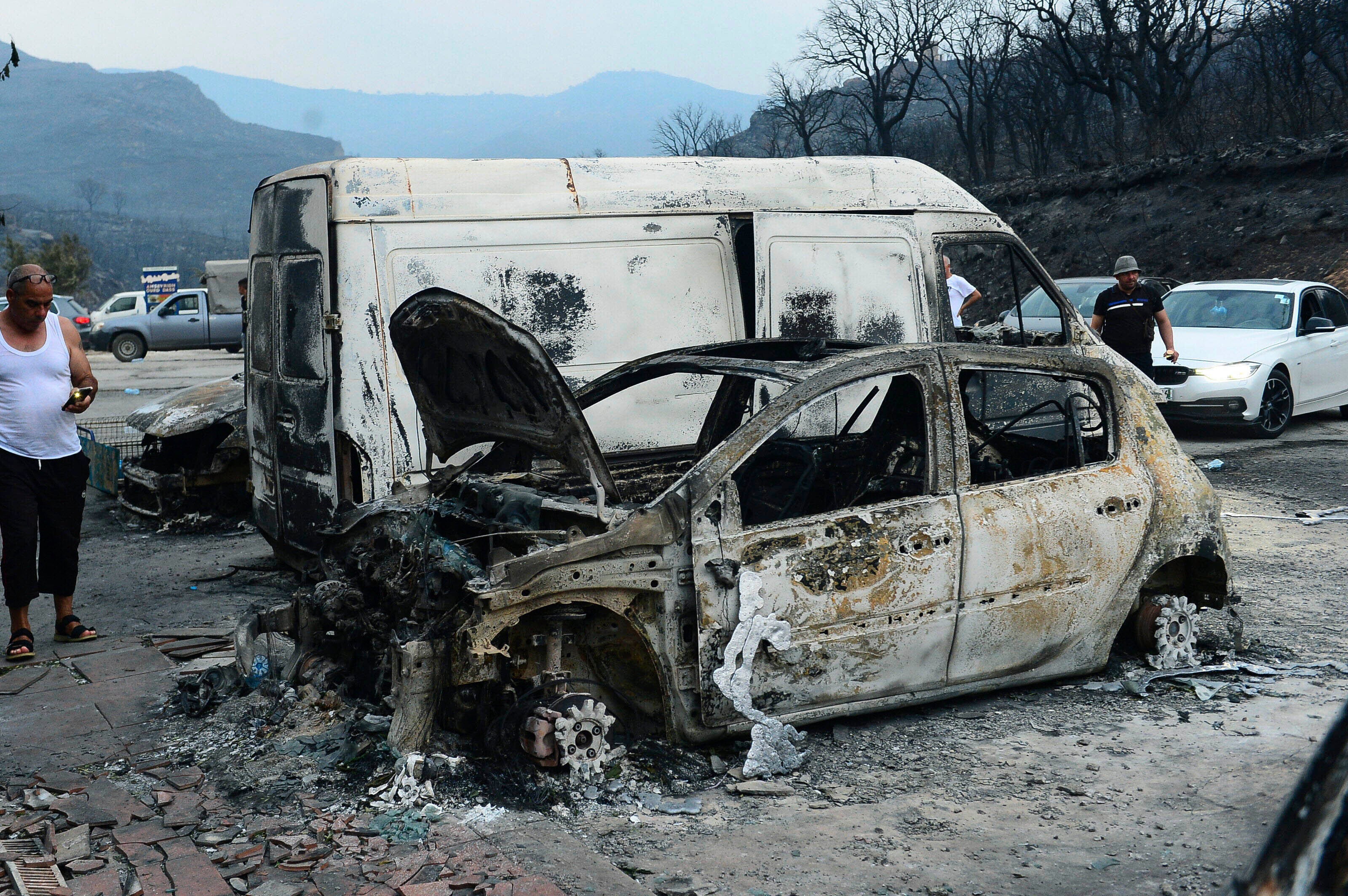 People inspect burnt vehicles after wildfire devastates Bouira, 100 km from Algiers
