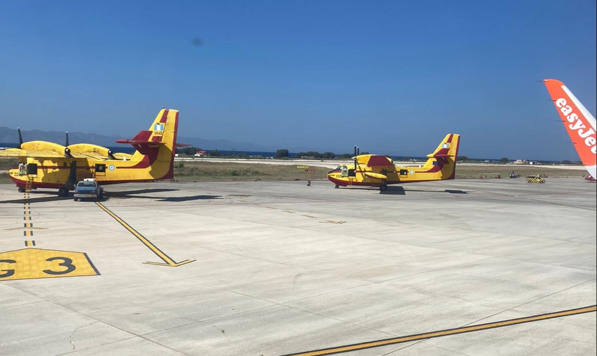 Firefighting planes sit on the tarmac as easyJet flight 8229 pulls into Rhodes airport
