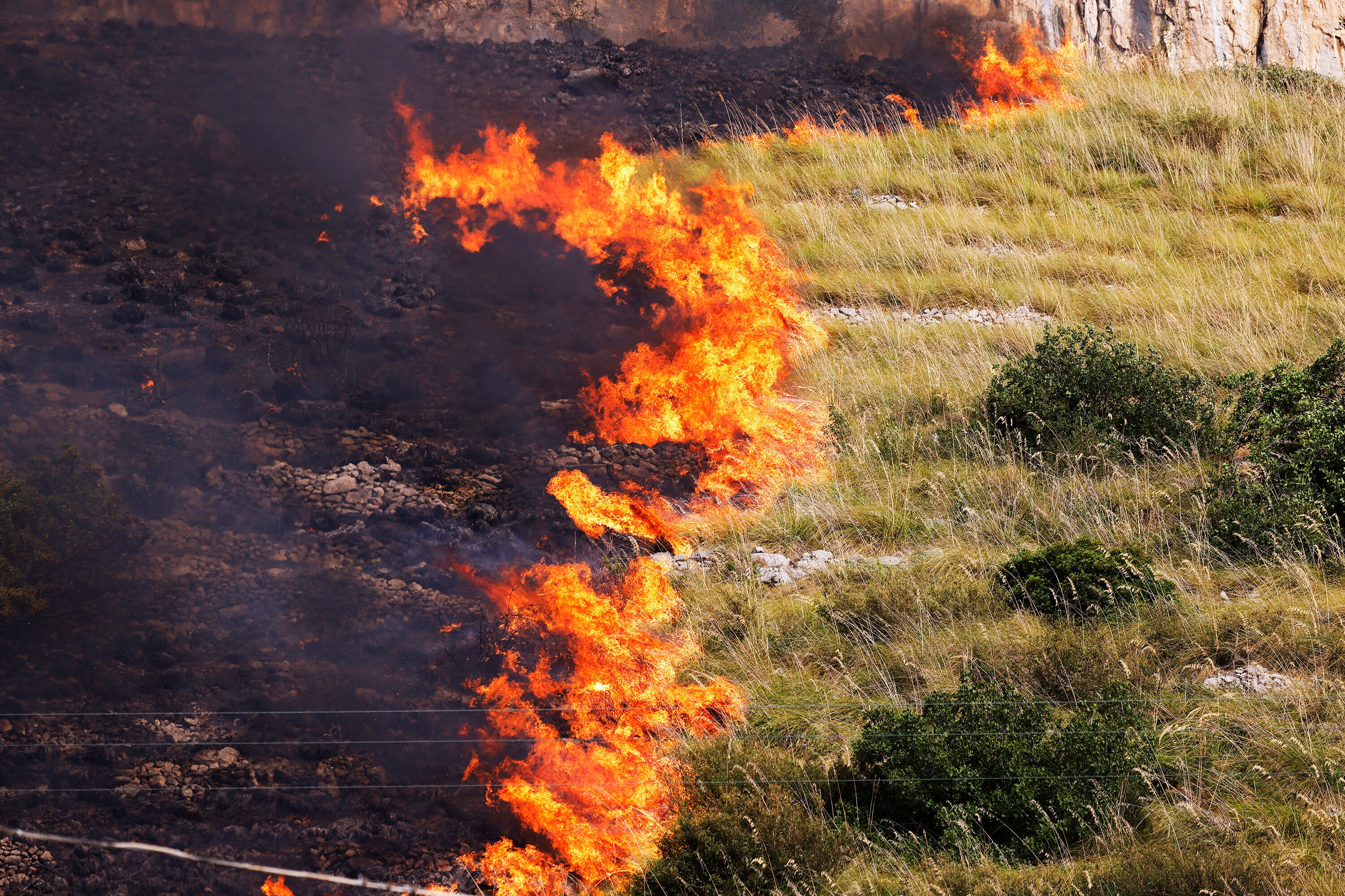 Flames burn in a field in Capaci, near Palermo, in Sicily, southern Italy