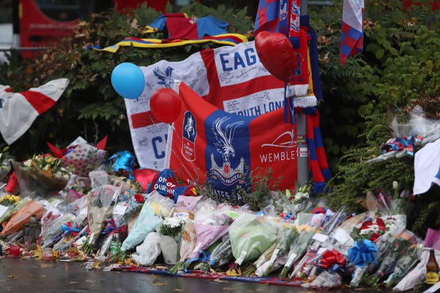 Floral tributes and Crystal Palace football colours left near the scene where a tram crashed, killing seven people, in Croydon, south London (PA)