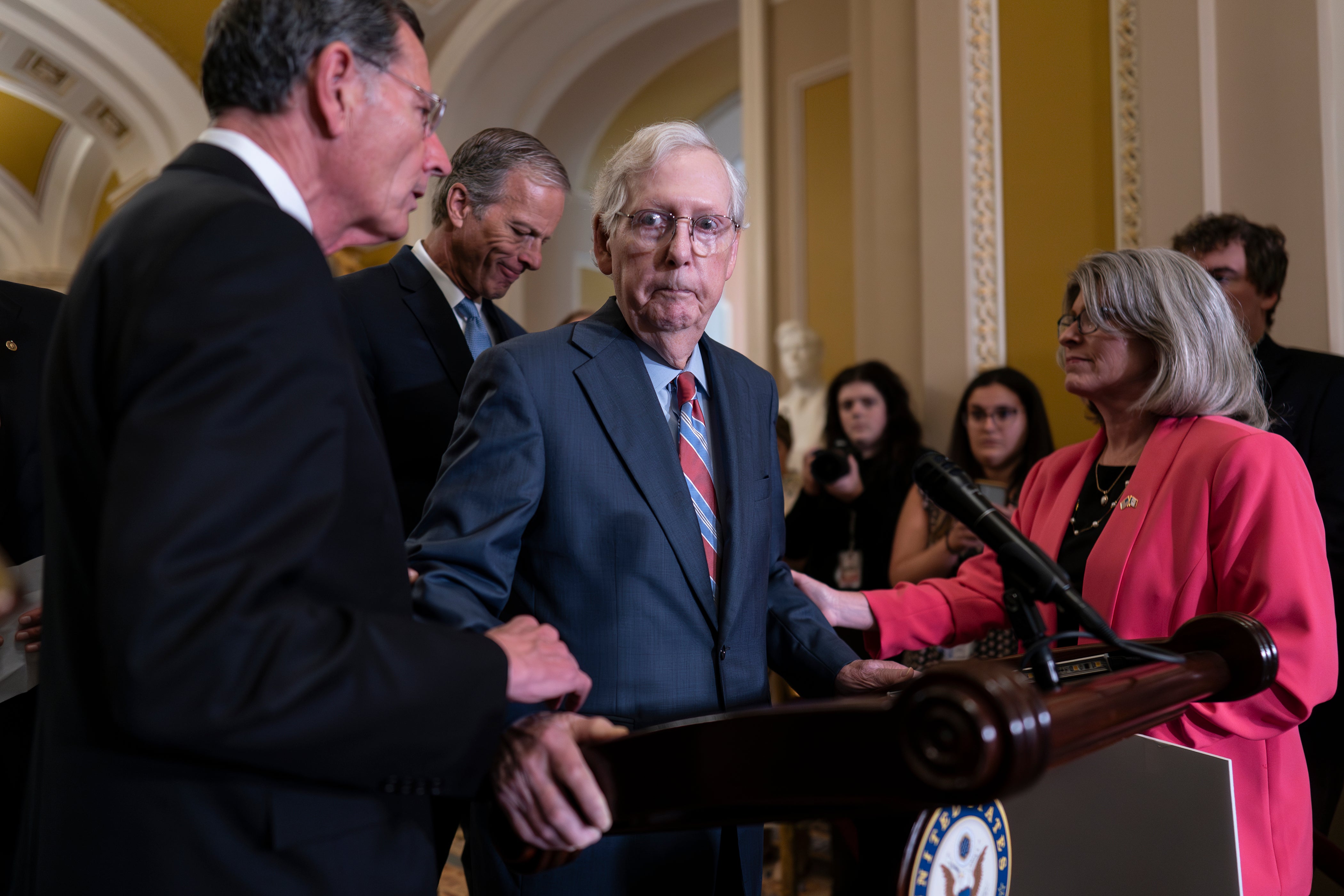 Senator Mitch McConnell is helped away from podium