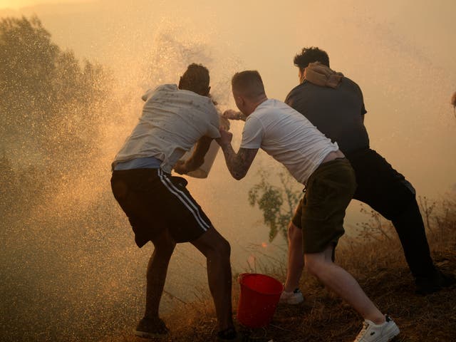 residents use buckets with water to try to slow down flames approaching their houses in Alcabideche, outside Lisbon