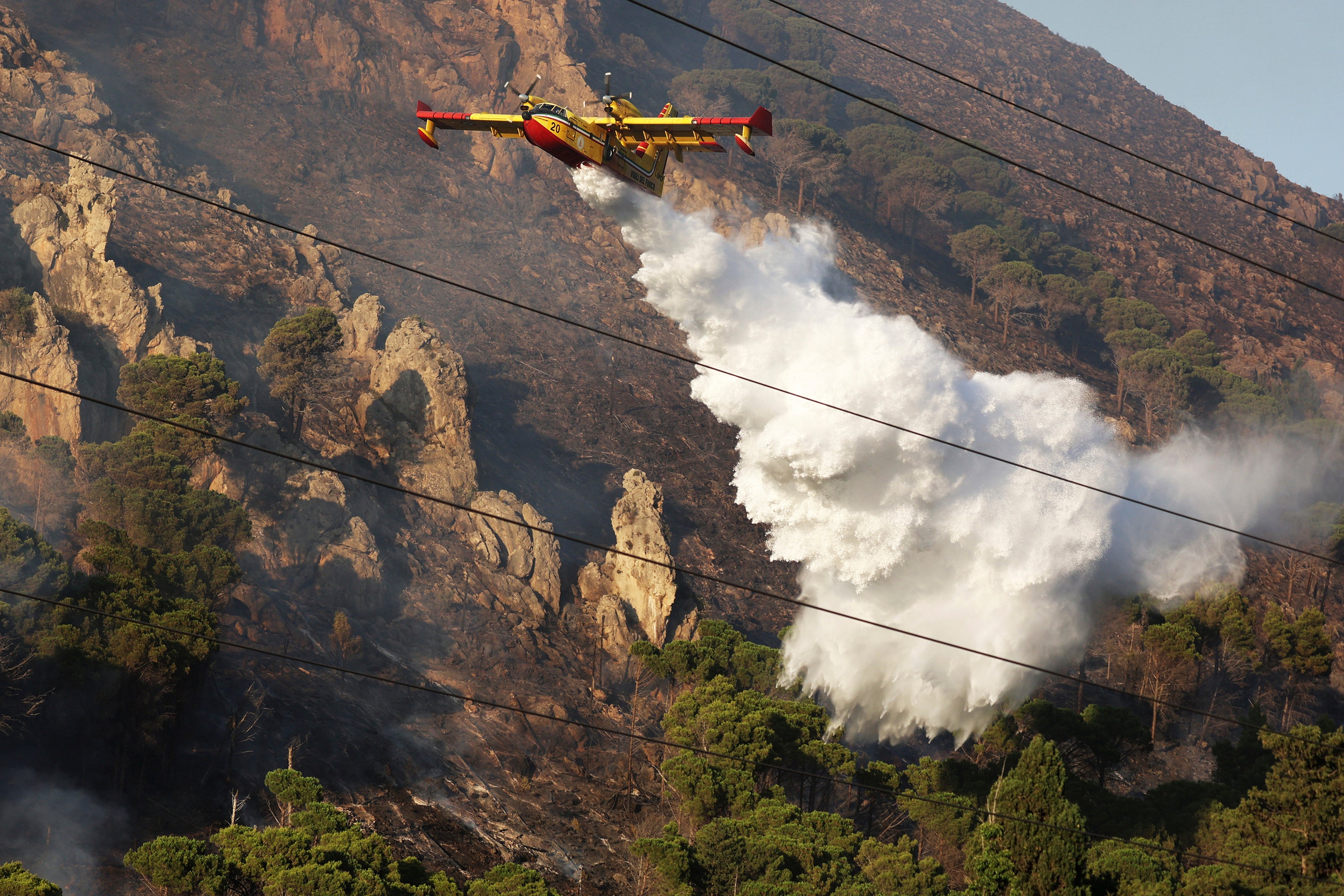 A firefighting plane drains water on a wildfire on the mountain in Altofonte near Palermo, Italy