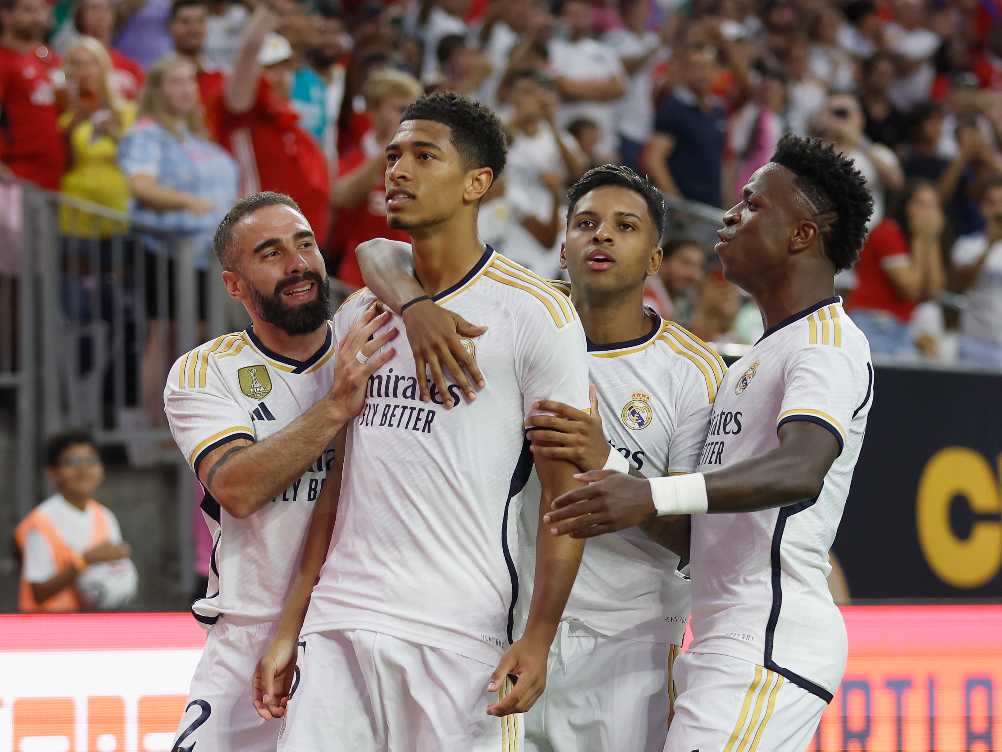  Four Real Madrid players celebrate a goal during a soccer match, with Jude Bellingham looking on.