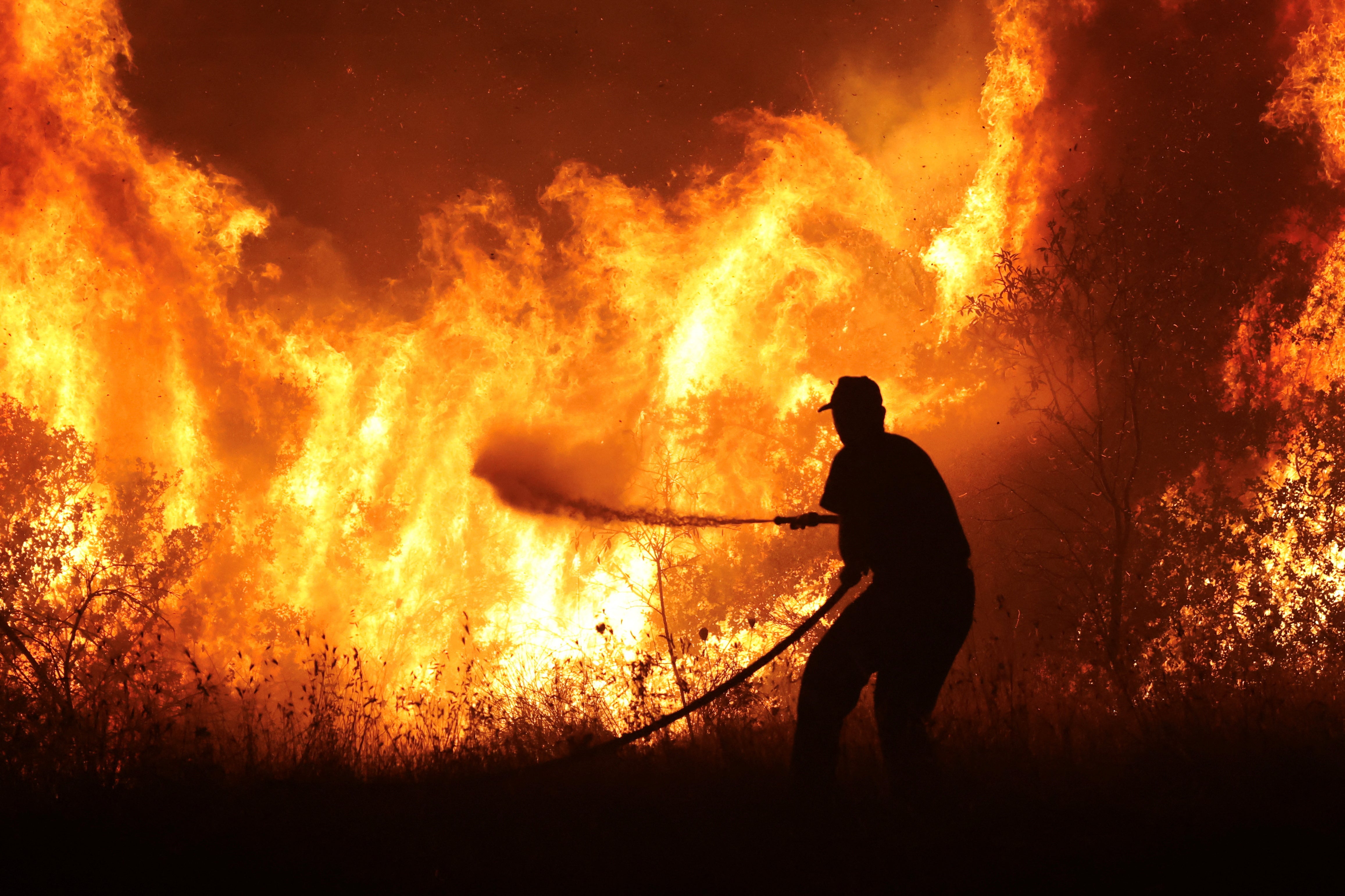 A firefighter tries to extinguish a wildfire burning at the industrial zone of the city of Volos, in central Greece