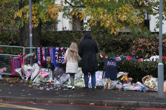 People look at floral tributes and Crystal Palace football colours left near the scene of the Croydon tram crash (Steve Parsons/PA)