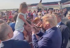 Little girl looks bemused as Trump signs autograph on her hand in permanent marker