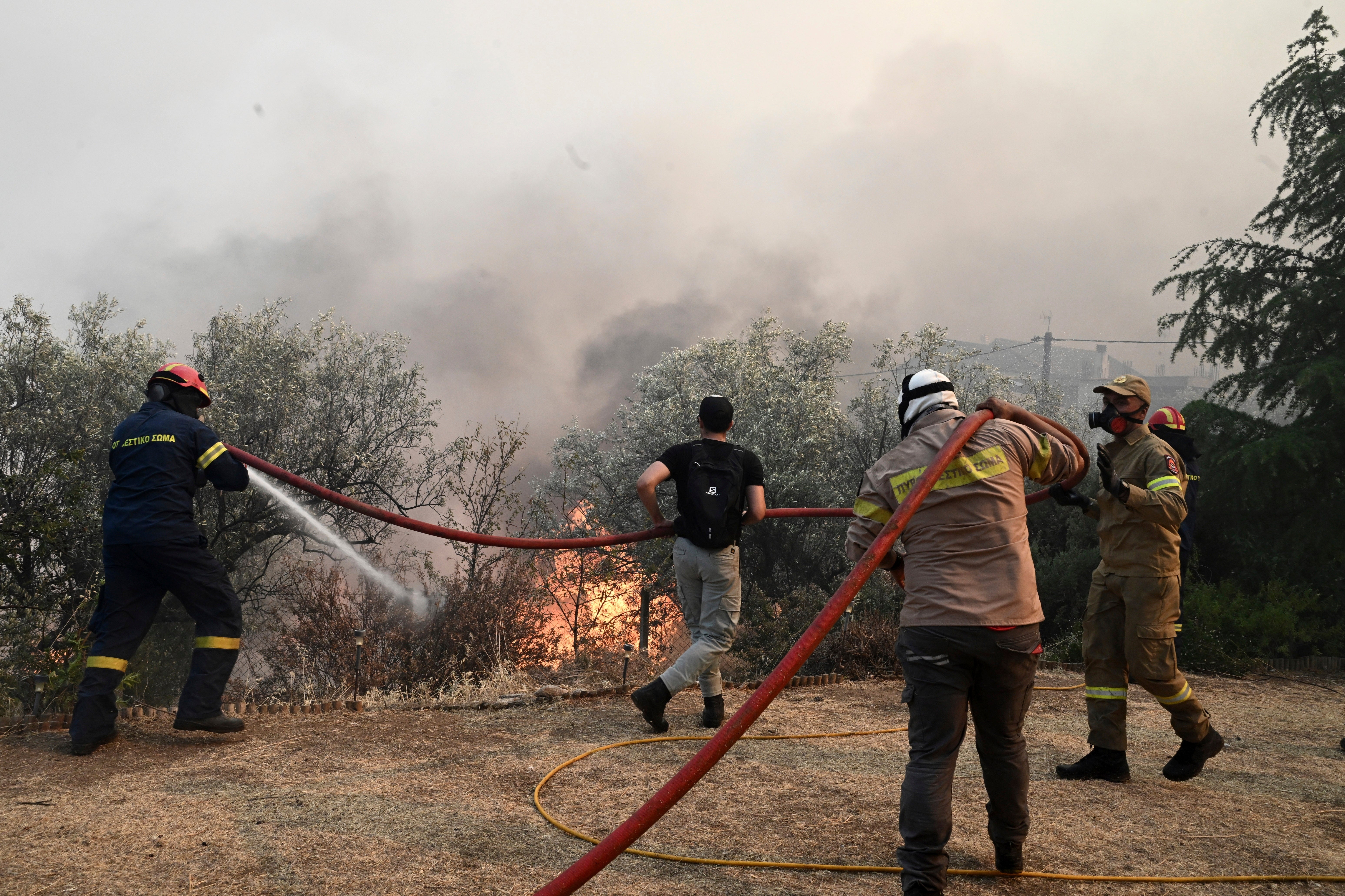 Firefighters and volunteers try to extinguish a wildfire in the town of Nea Anchialos, near Volos city, central Greece