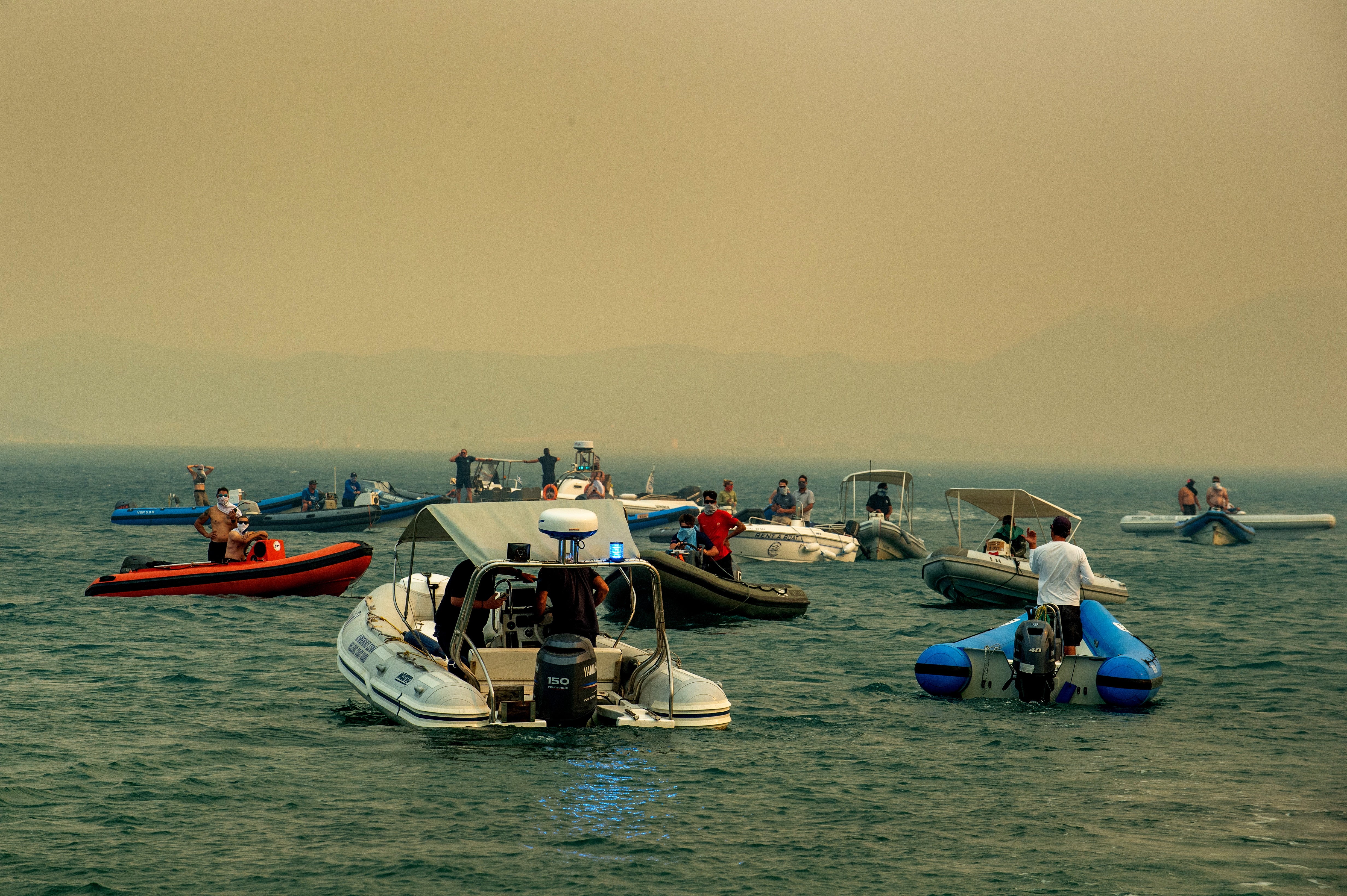 People evacuate by boats during a wildfire at Nea Anchialos, near Volos, Greece