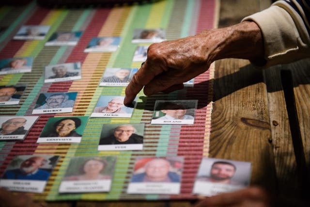 <p>An Alzheimer patient points to a photograph of a former Alzheimer patients who used to visit “Les Papillons de Marcelle” at the center in Arles, southeastern France, on May 9, 2023</p>