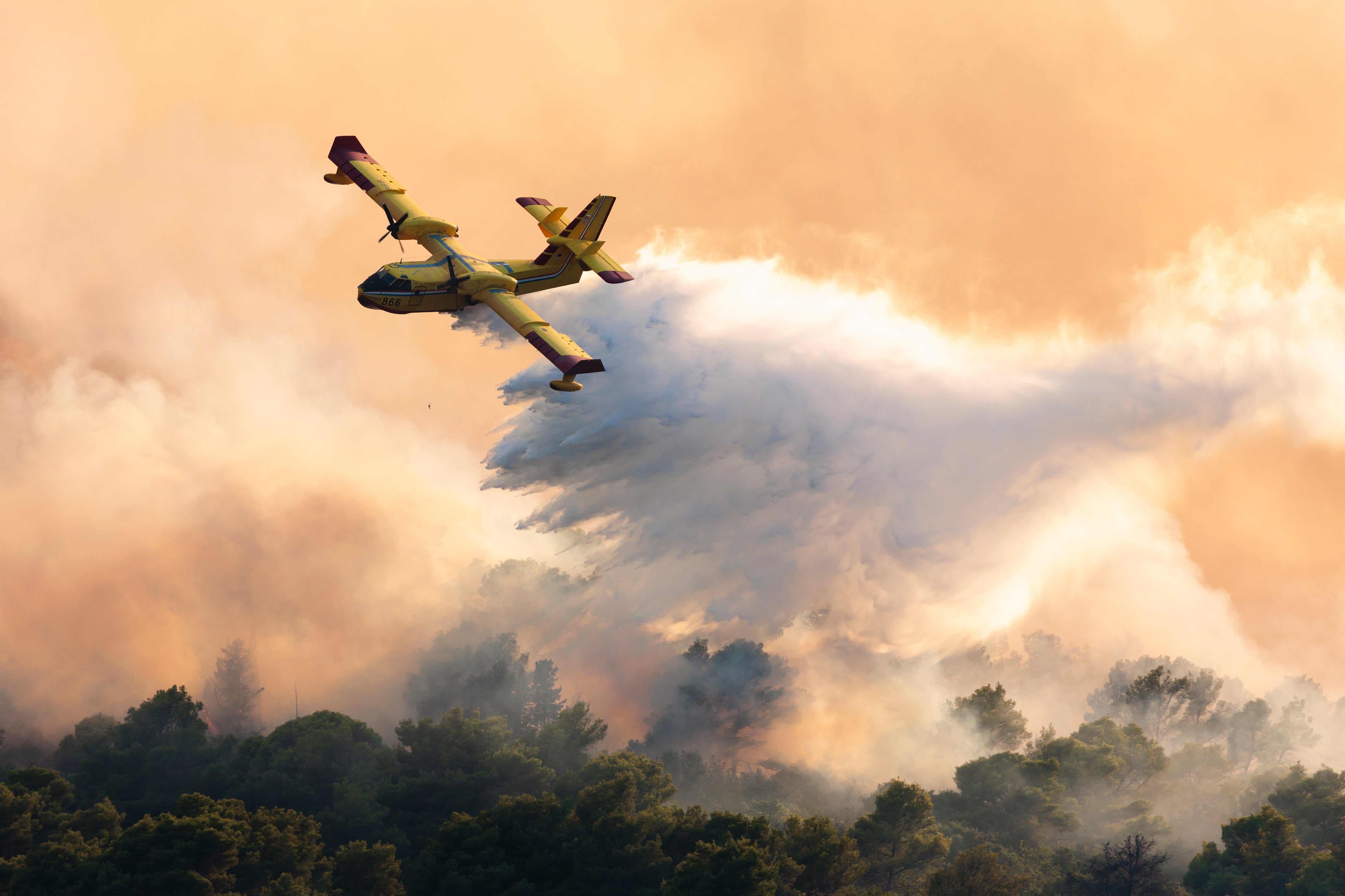 A firefighting plane sprays water to extinguish wildfire at Ciovo island, Croatia