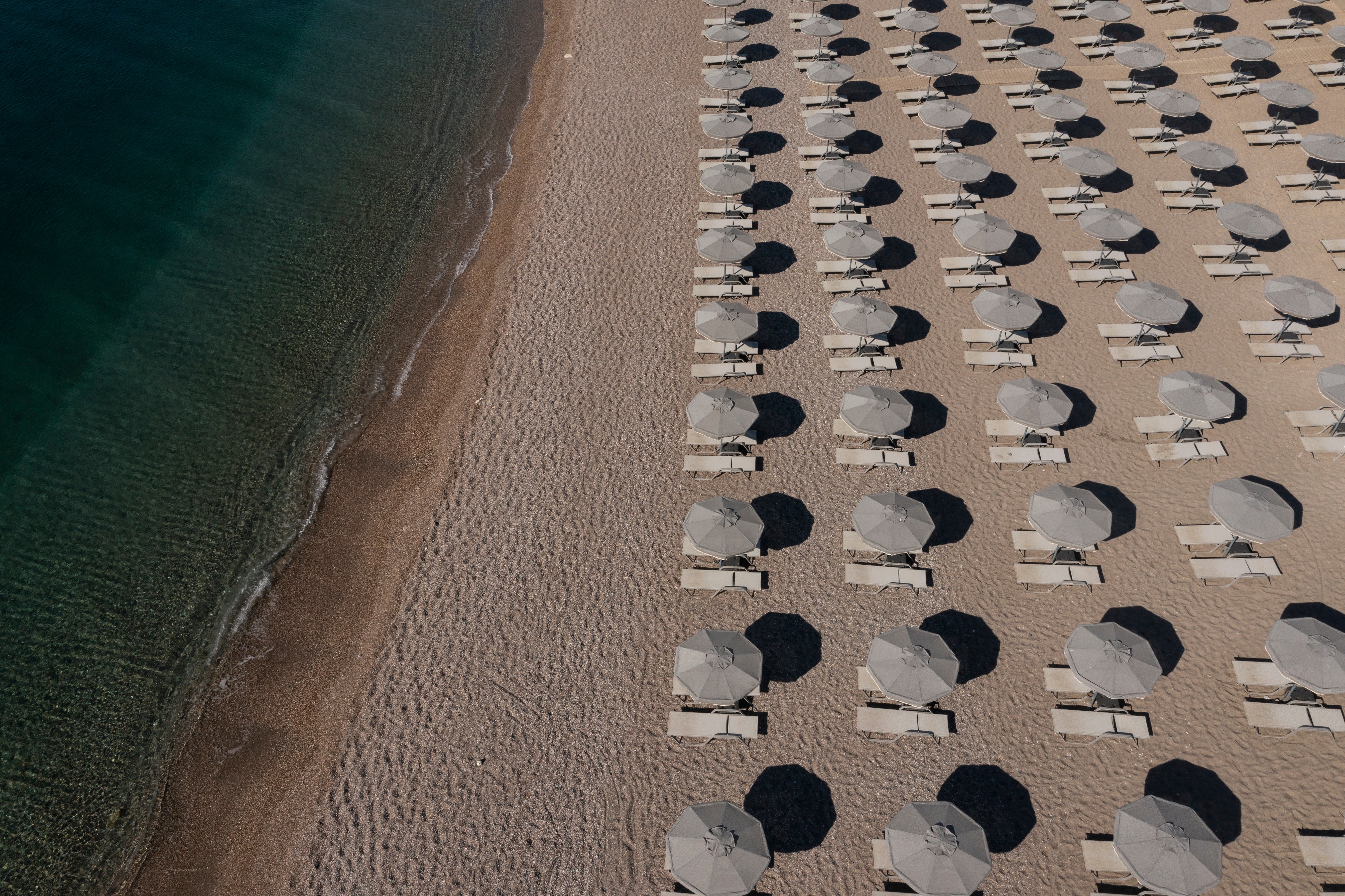 In an aerial view, empty sun loungers line the beach at a resort on July 28, 2023 in Gennadi, Rhodes, Greece