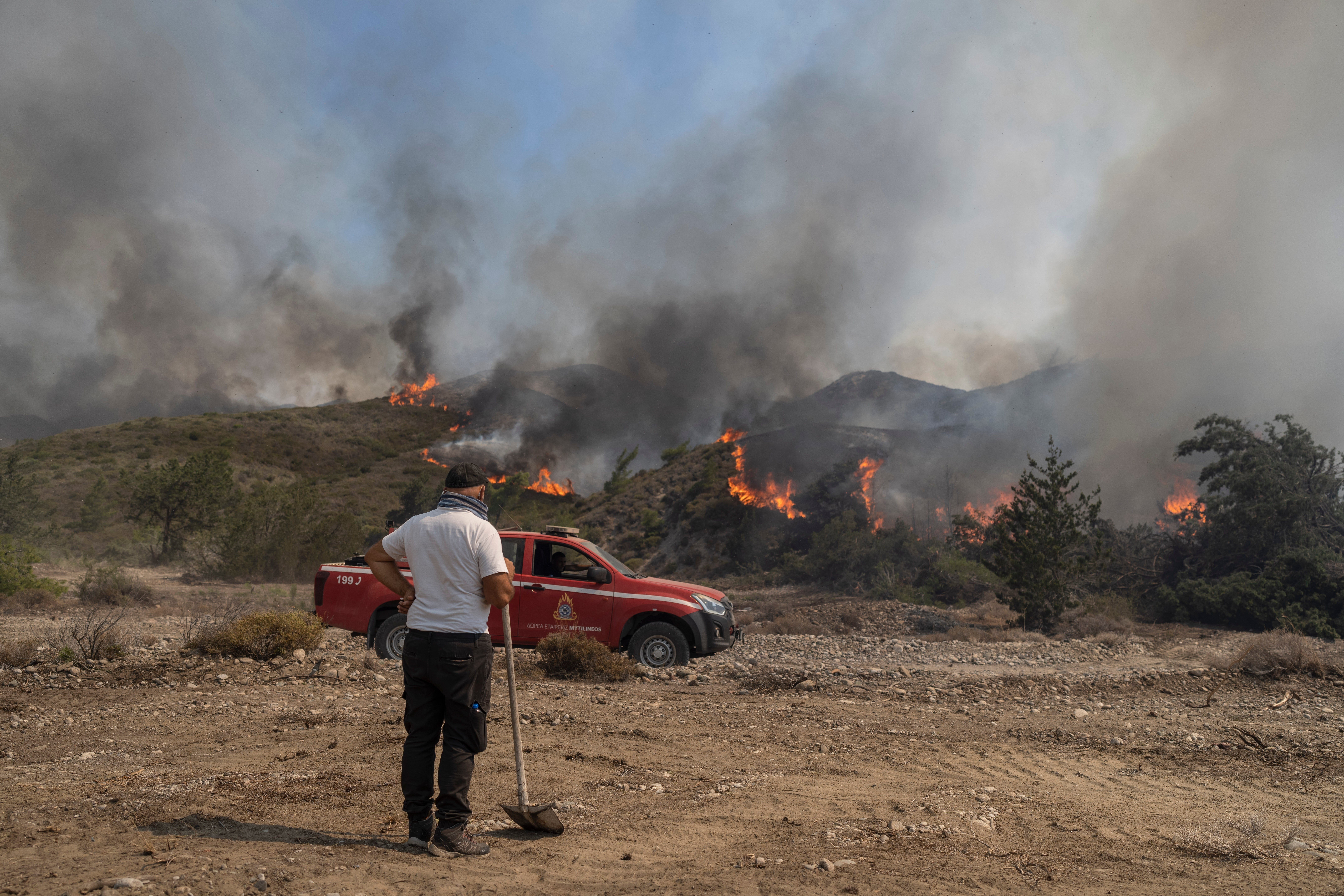 A man watches the fire burning a forest in Vati village, on the Aegean Sea island of Rhodes,