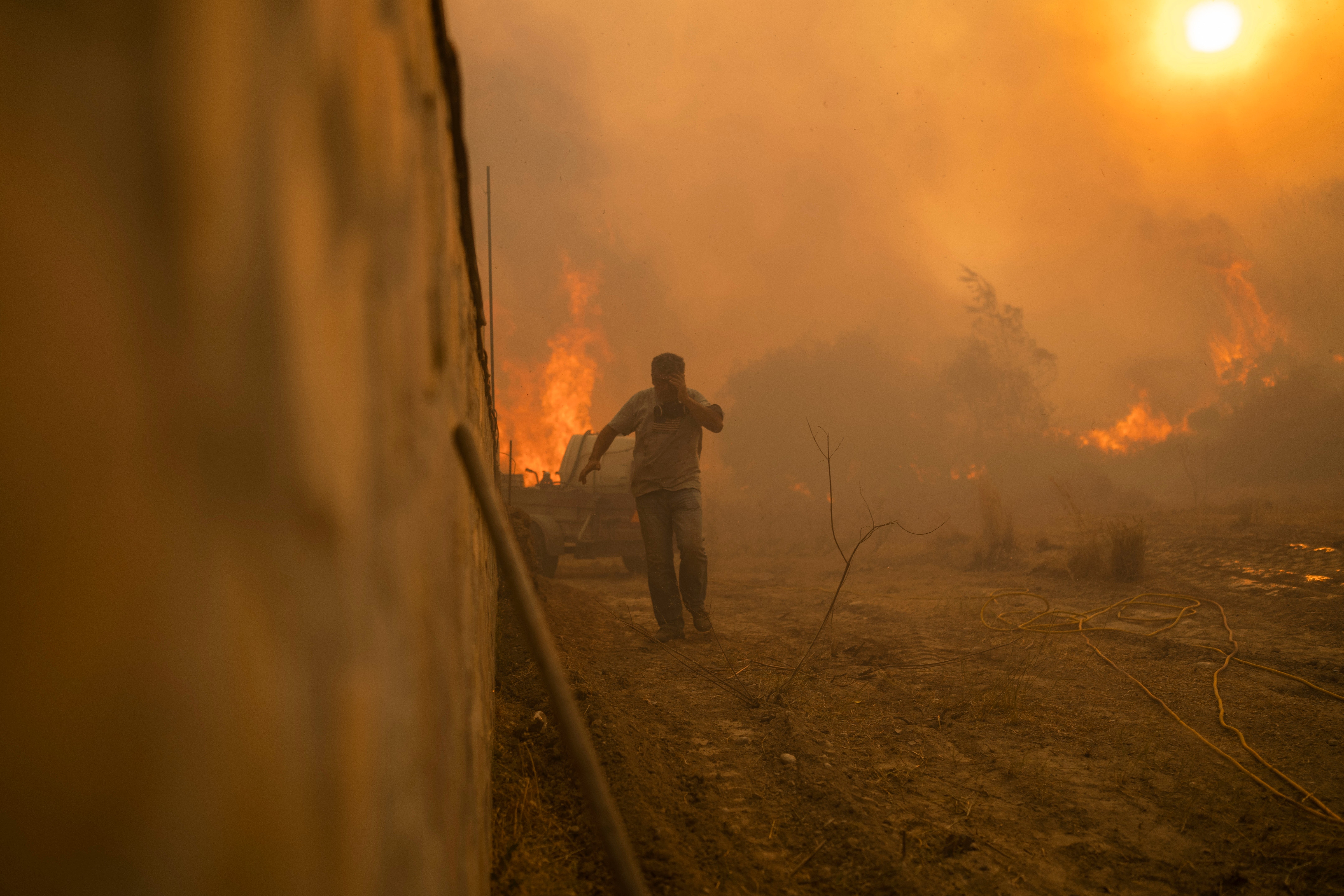 A local runs to avoid the flames of a wildfire in Gennadi village, on the Aegean Sea island of Rhodes, southeastern Greece, on July 25, 2023