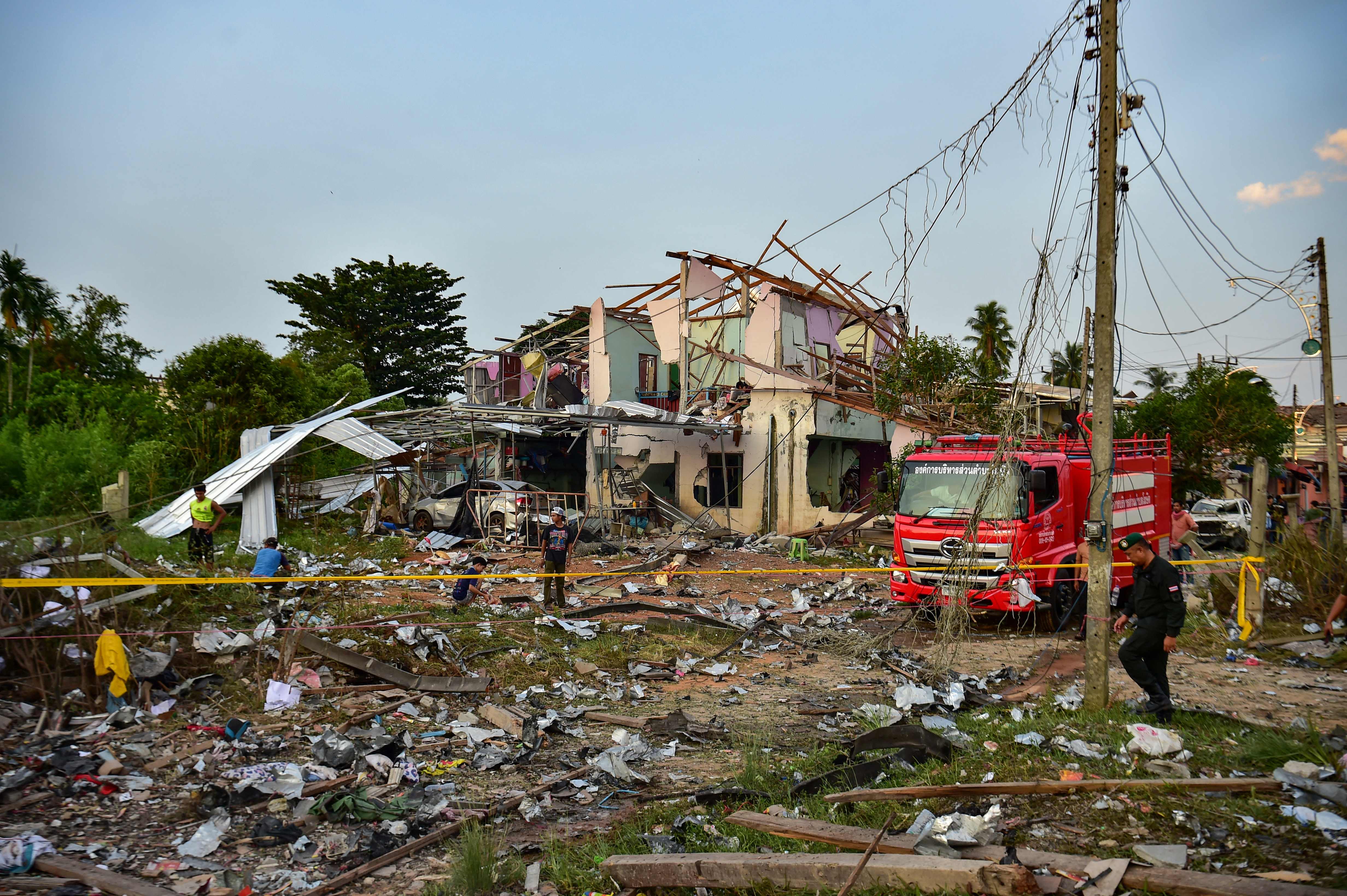 Thai police, rescue crew and locals gather around destroyed homes after an explosion ripped through a firework warehouse