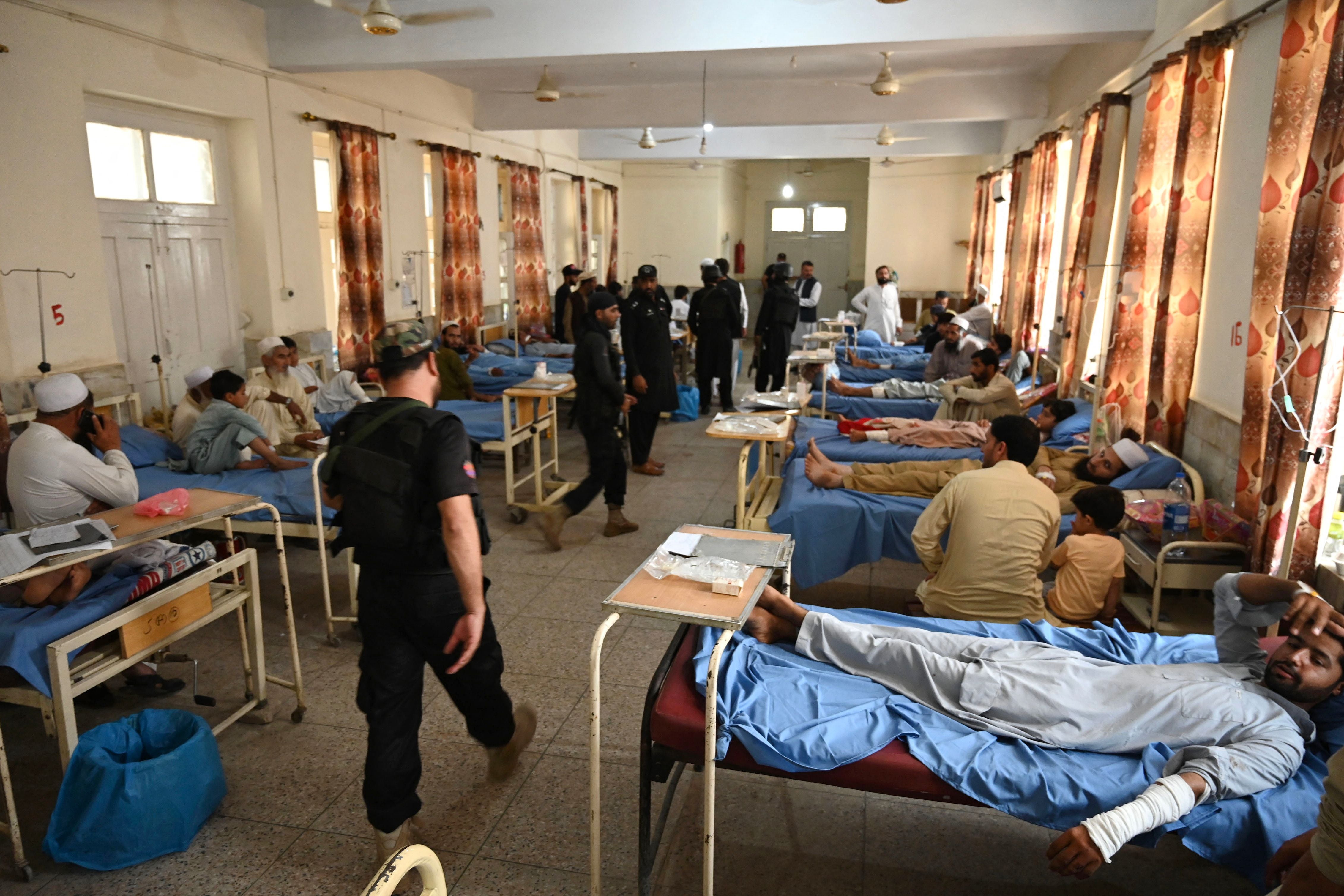 Security personnel walk past bomb blast victims at a hospital