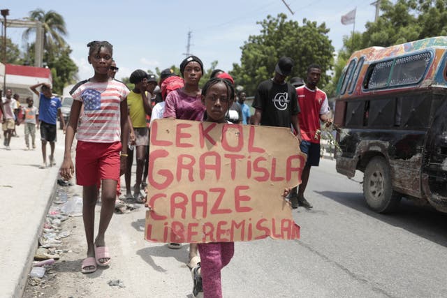 <p>A girl carries a sign that reads in Creole "Free school is broken. Release the nurse," during a march to demand the freedom of New Hampshire nurse Alix Dorsainvil and her daughter, who have been reported kidnapped</p>