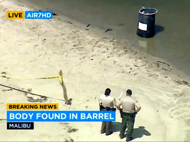 <p>Law enforcement officers stand near a barrel in which a human body was discovered at Malibu Lagoon State Beach, California on Monday 31 July</p>