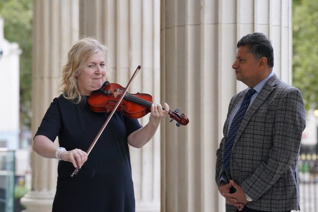 <p>Dagmar Turner playing the violin as she was reunited with consultant neurosurgeon Professor Keyoumars Ashkan</p>