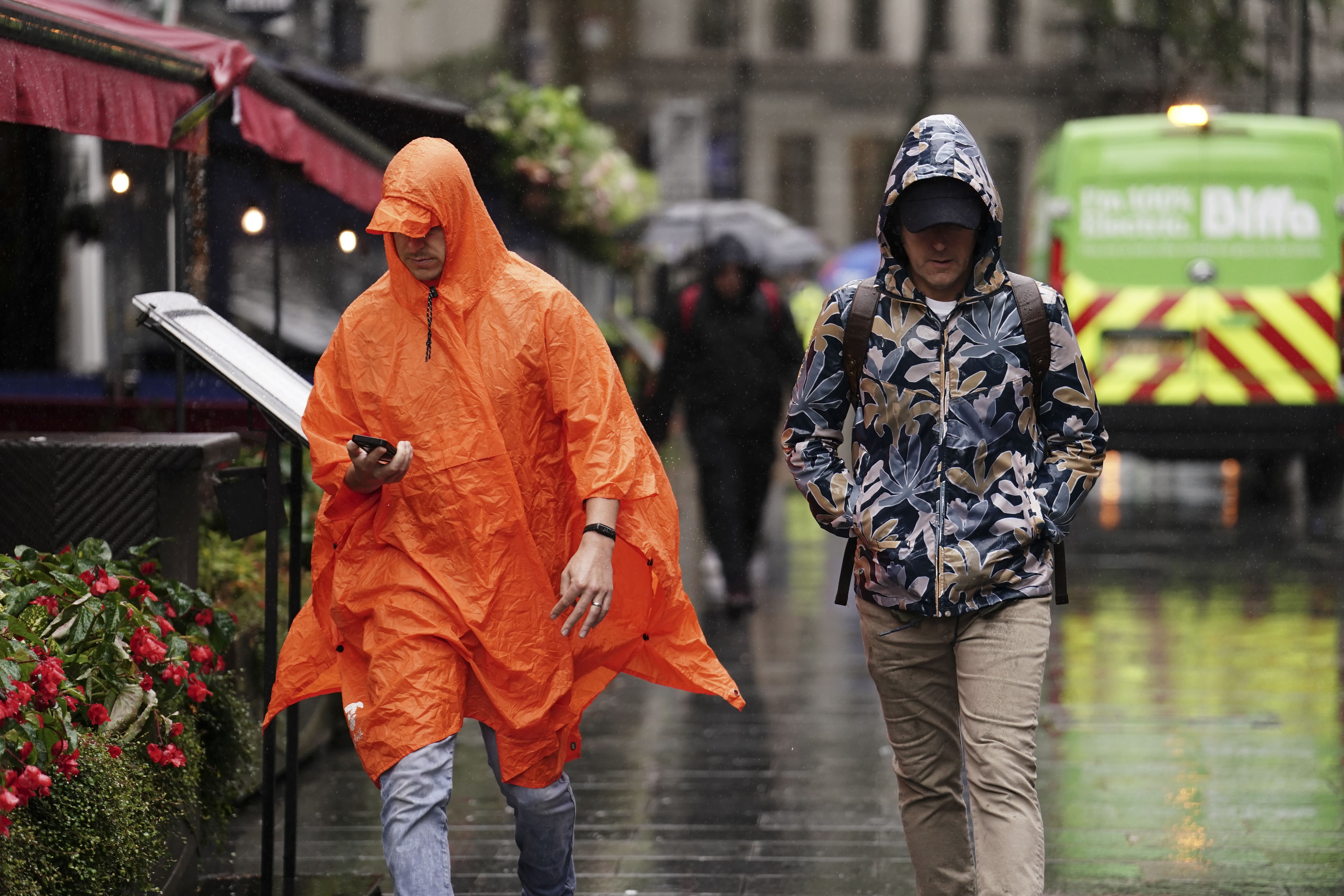 People caught during a heavy downpour of rain in Leicester Square, London (Jordan Pettitt/PA)