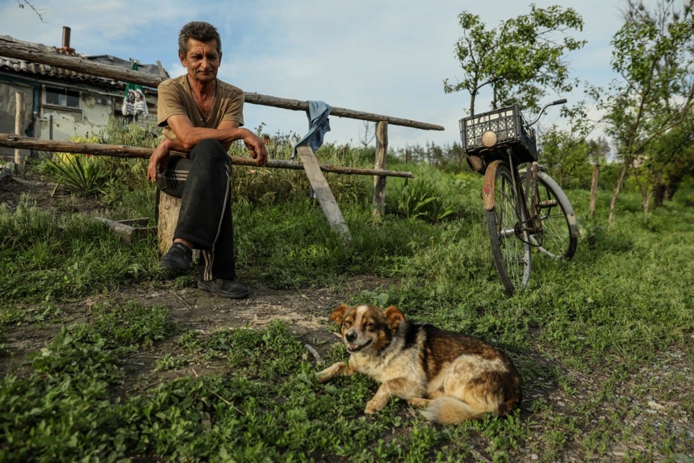 Mykola and his dog sit in front of his house