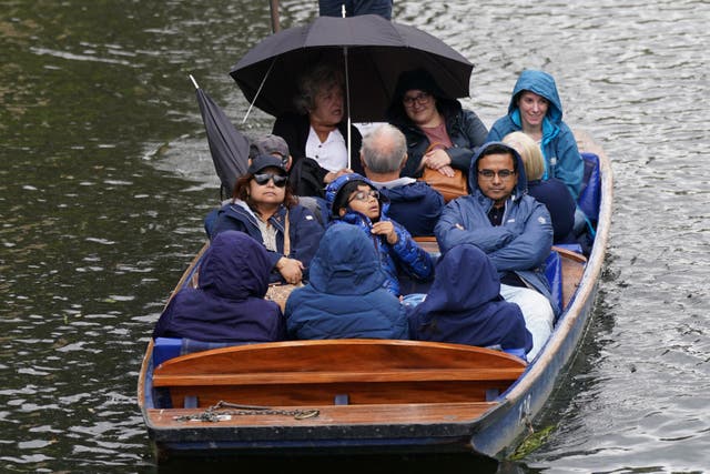 People wrap up against the rain on a punt on the River Cam in Cambridge (Joe Giddens/PA)
