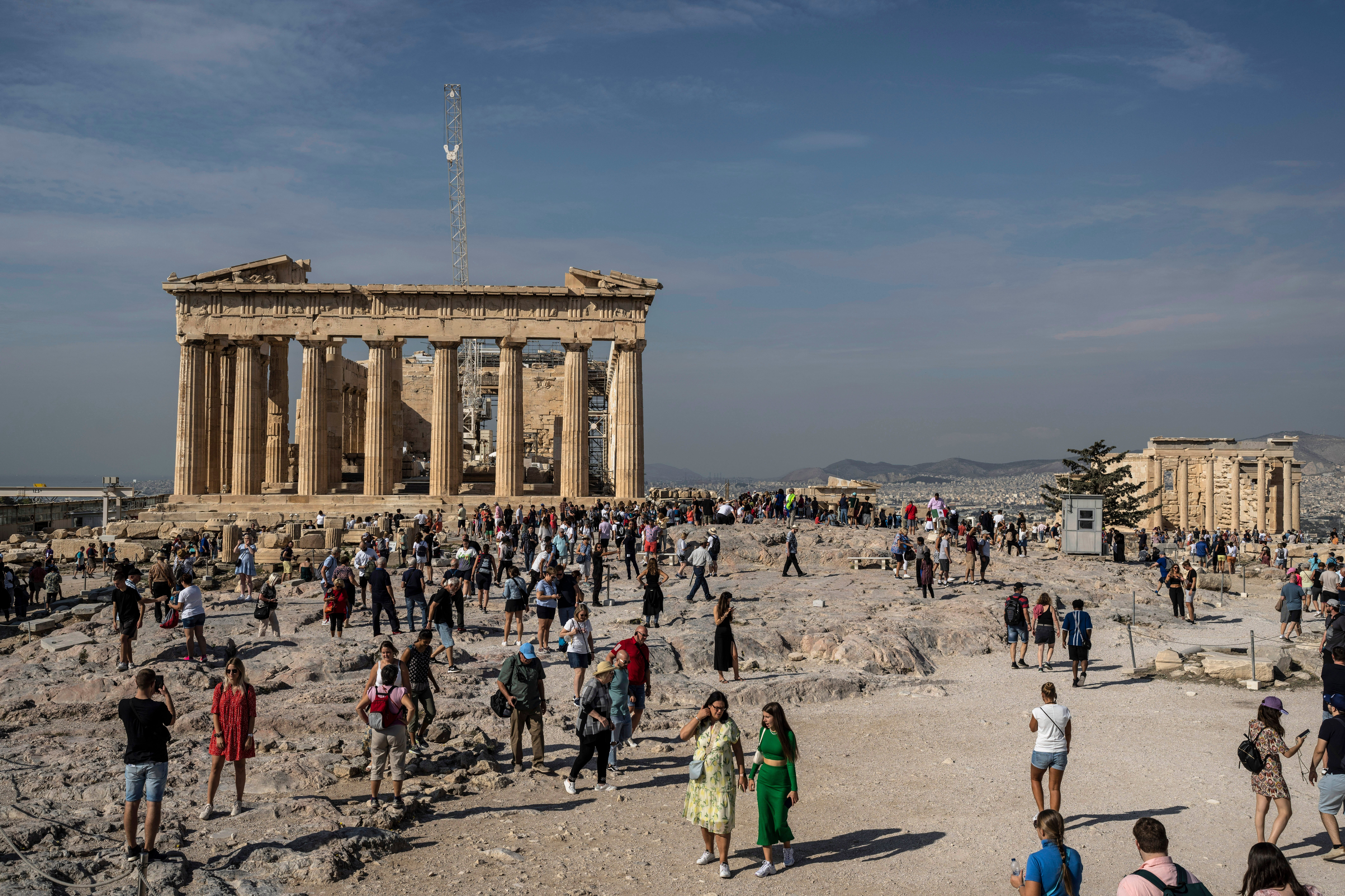 Tourists visit the Acropolis hill, with the 2,500-year-old Parthenon temple on the left