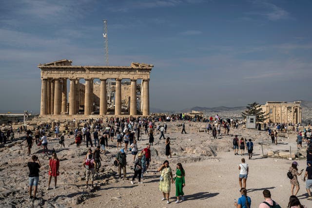 <p>Tourists visit the Acropolis hill, with the 2,500-year-old Parthenon temple on the left</p>