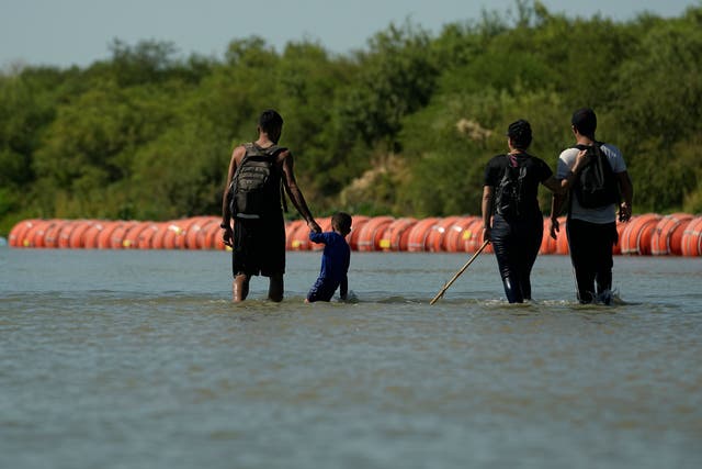 <p>Migrants crossing into the U.S. from Mexico walk along large buoys being used as a floating border barrier on the Rio Grande Tuesday, Aug. 1, 2023, in Eagle Pass, Texas</p>