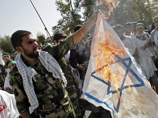 <p>A member of Iran’s Revolutionary Guards burns an Israeli flag during a demonstration in 2006</p>