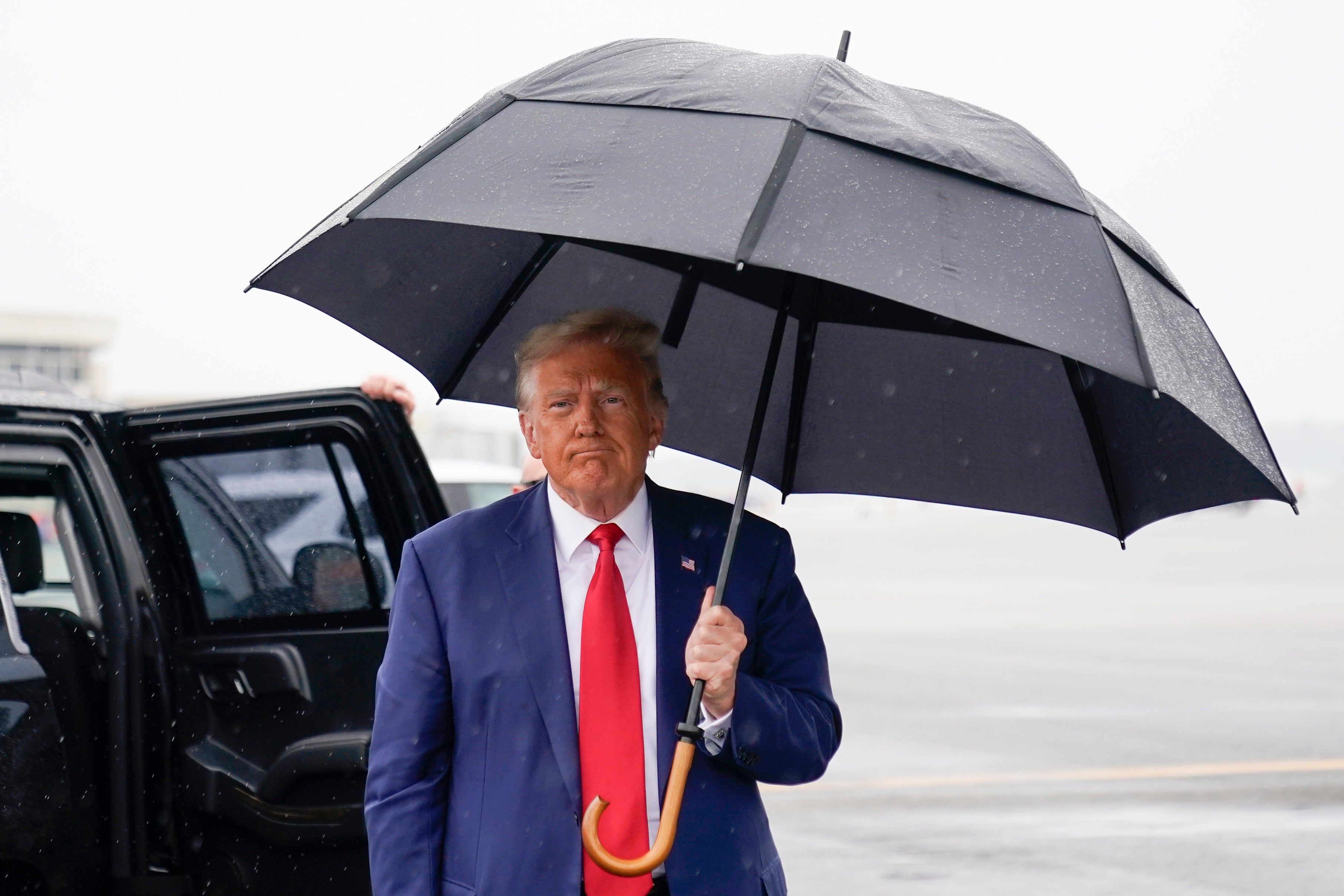 Former President Donald Trump walks over to speak with reporters on tarmac after his arraignment