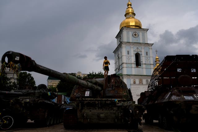 <p>A boy stands on top of a destroyed Russian tank exhibited outside St Michael's Golden-Domed Monastery in Kyiv</p>