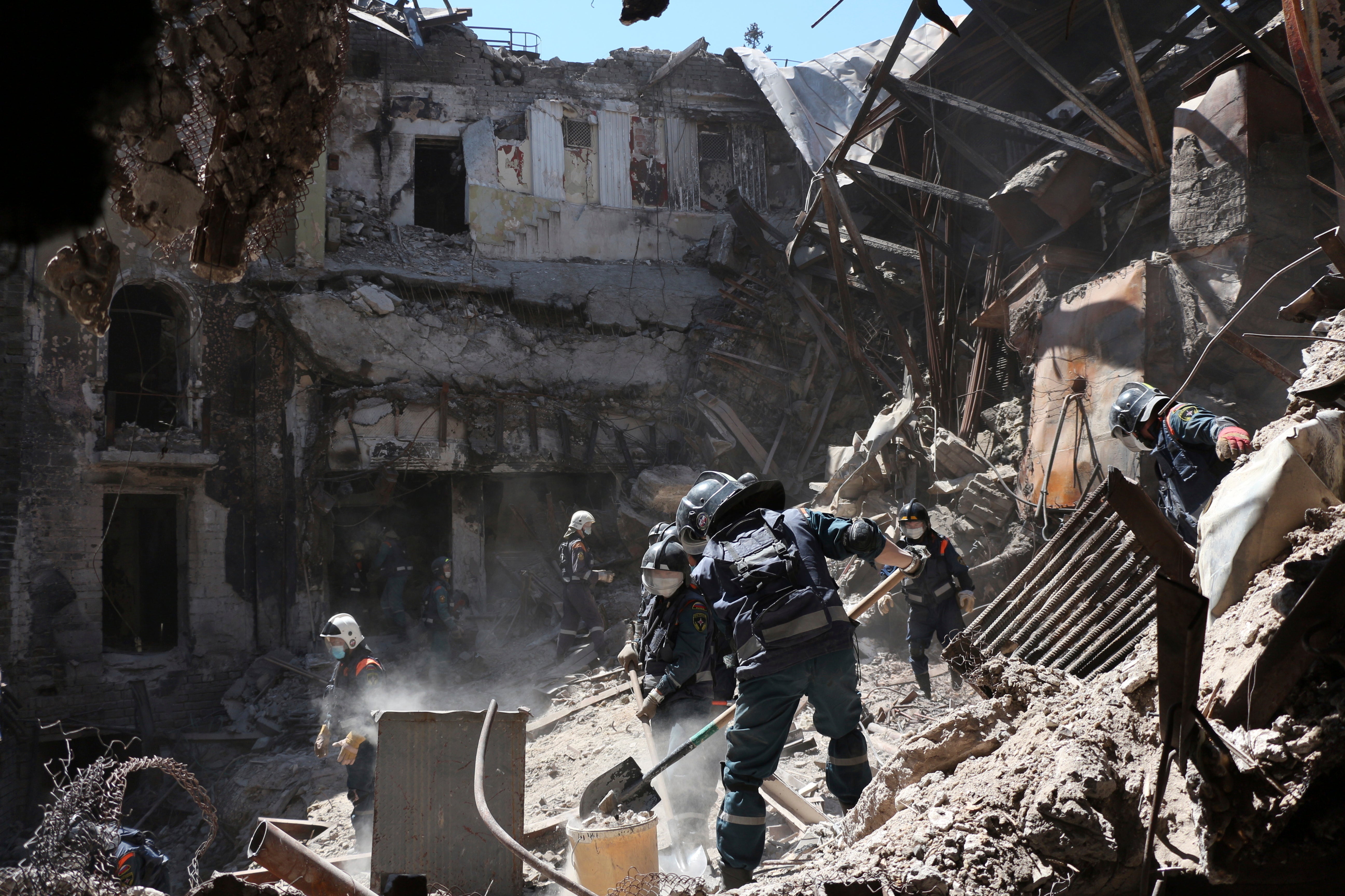 Donetsk People Republic Emergency Situations Ministry employees clear rubble at the side of the damaged Mariupol theatre after the attack
