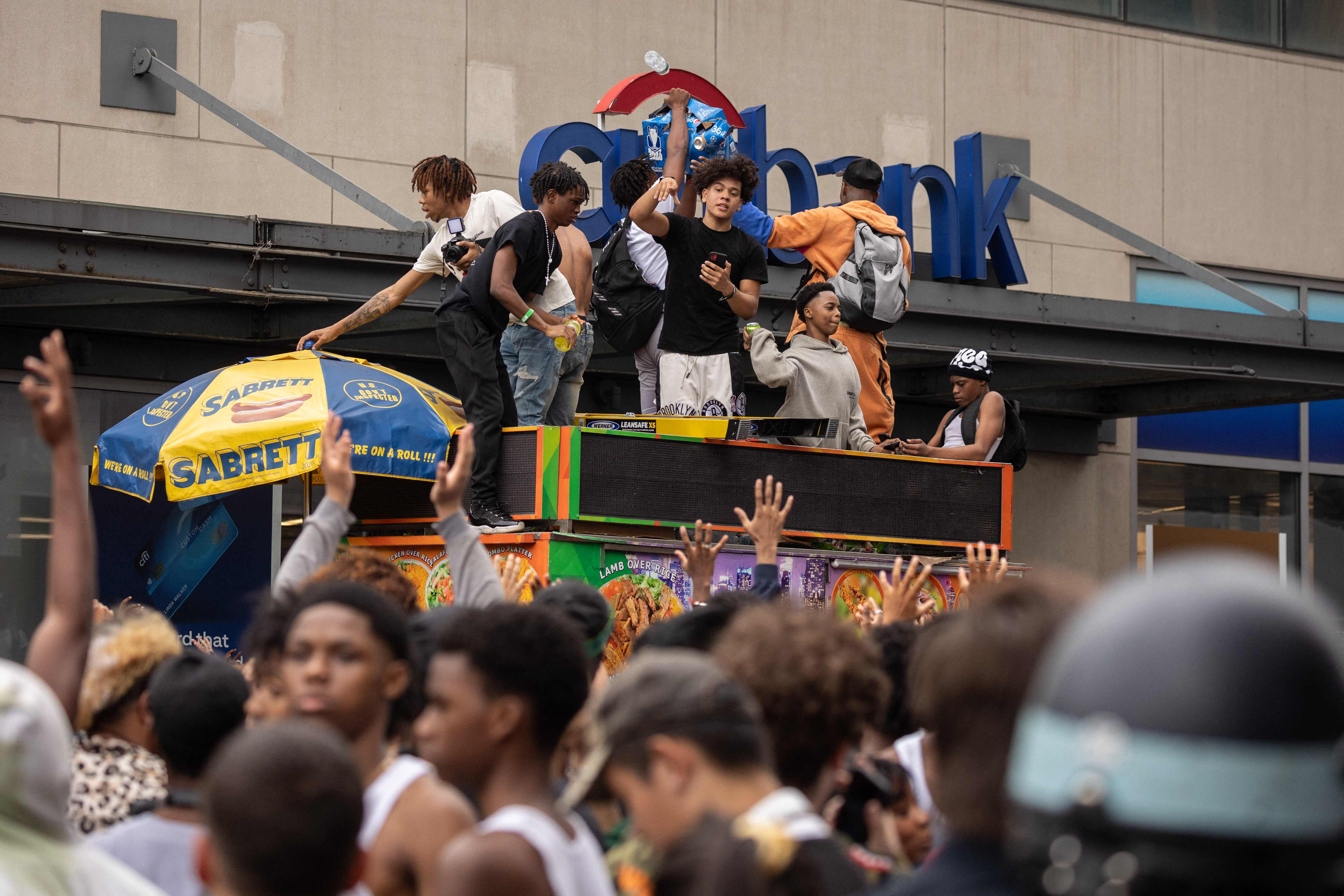 People stand on top of a street vendor's cart during the riot