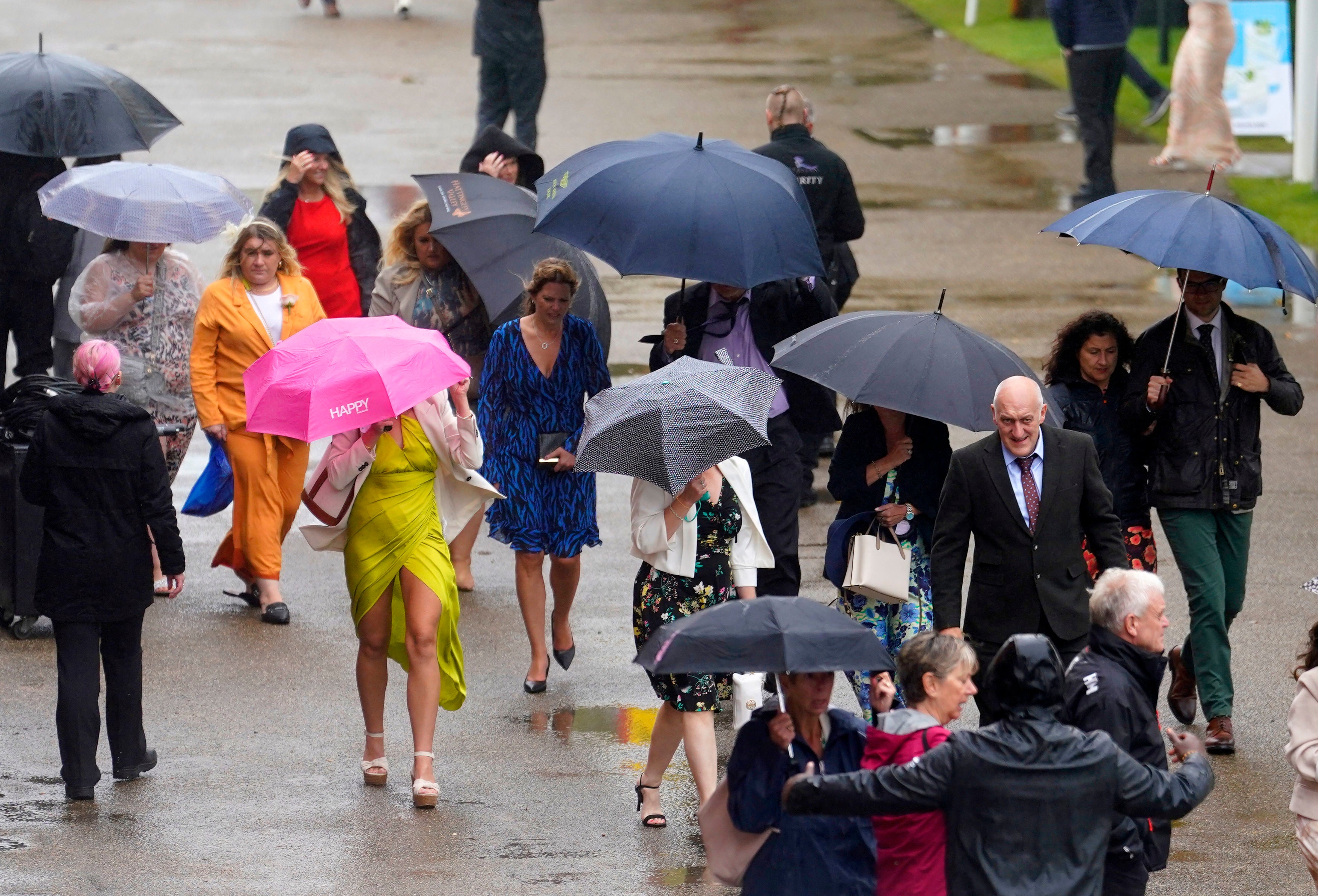 Racegoers shelter from the rain as they arrive for day five of the Qatar Goodwood Festival at Goodwood Racecourse