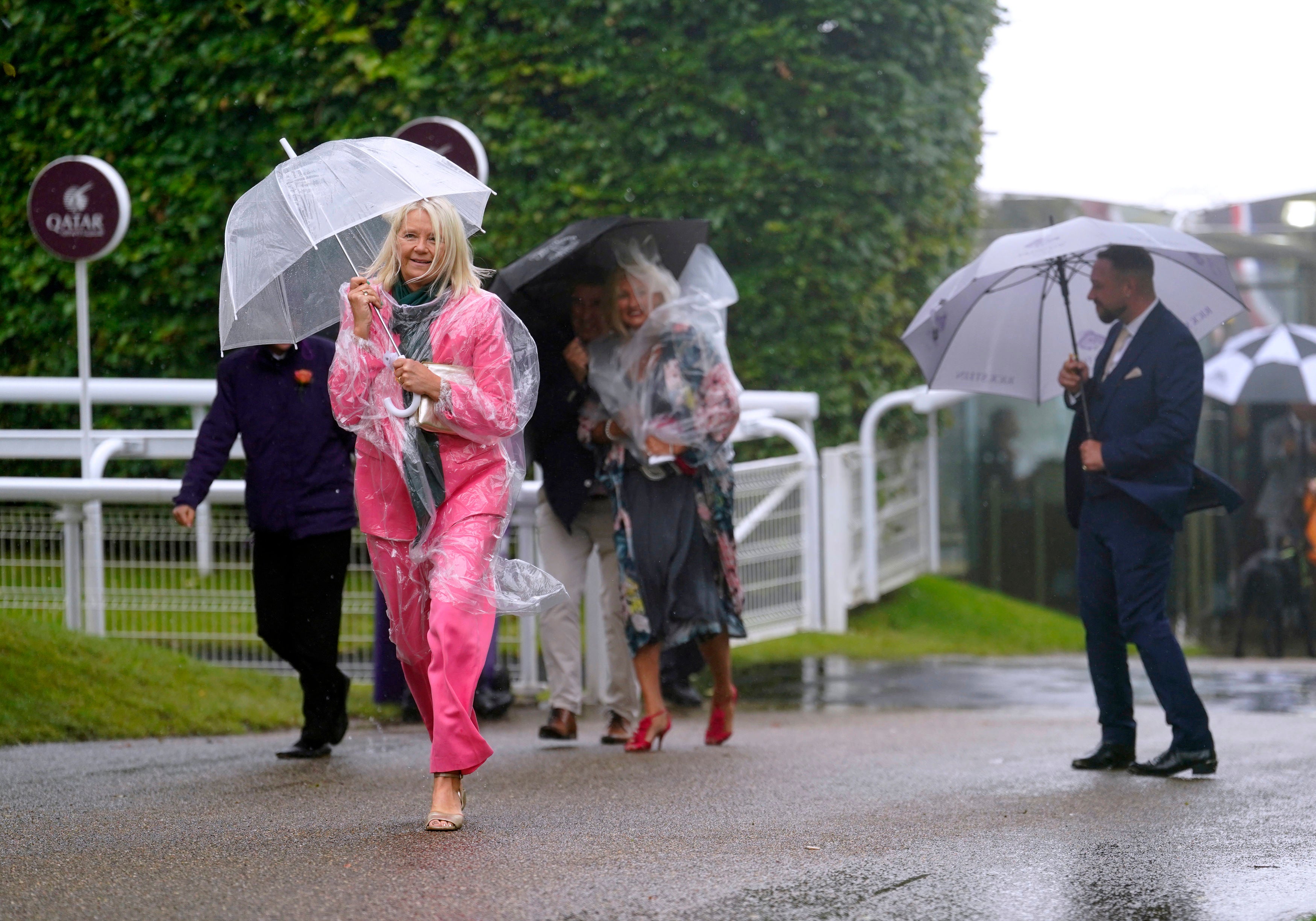 Racegoers shelter from the rain as they arrive for day five of the Qatar Goodwood Festival at Goodwood Racecourse