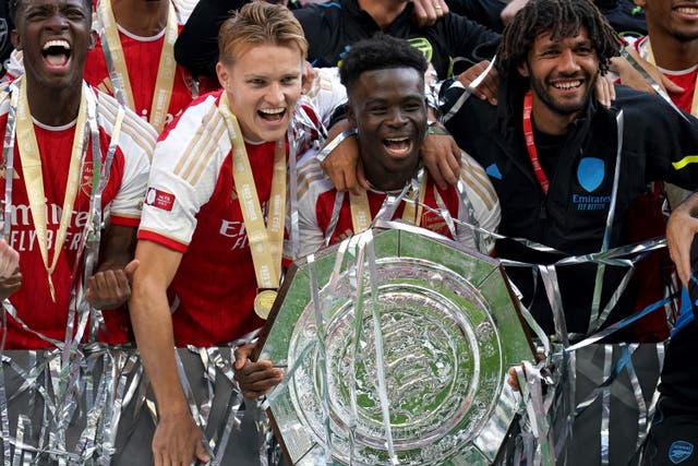 Arsenal’s Martin Odegaard (centre left) and Bukayo Saka celebrate with the Community Shield trophy (John Walton/PA)