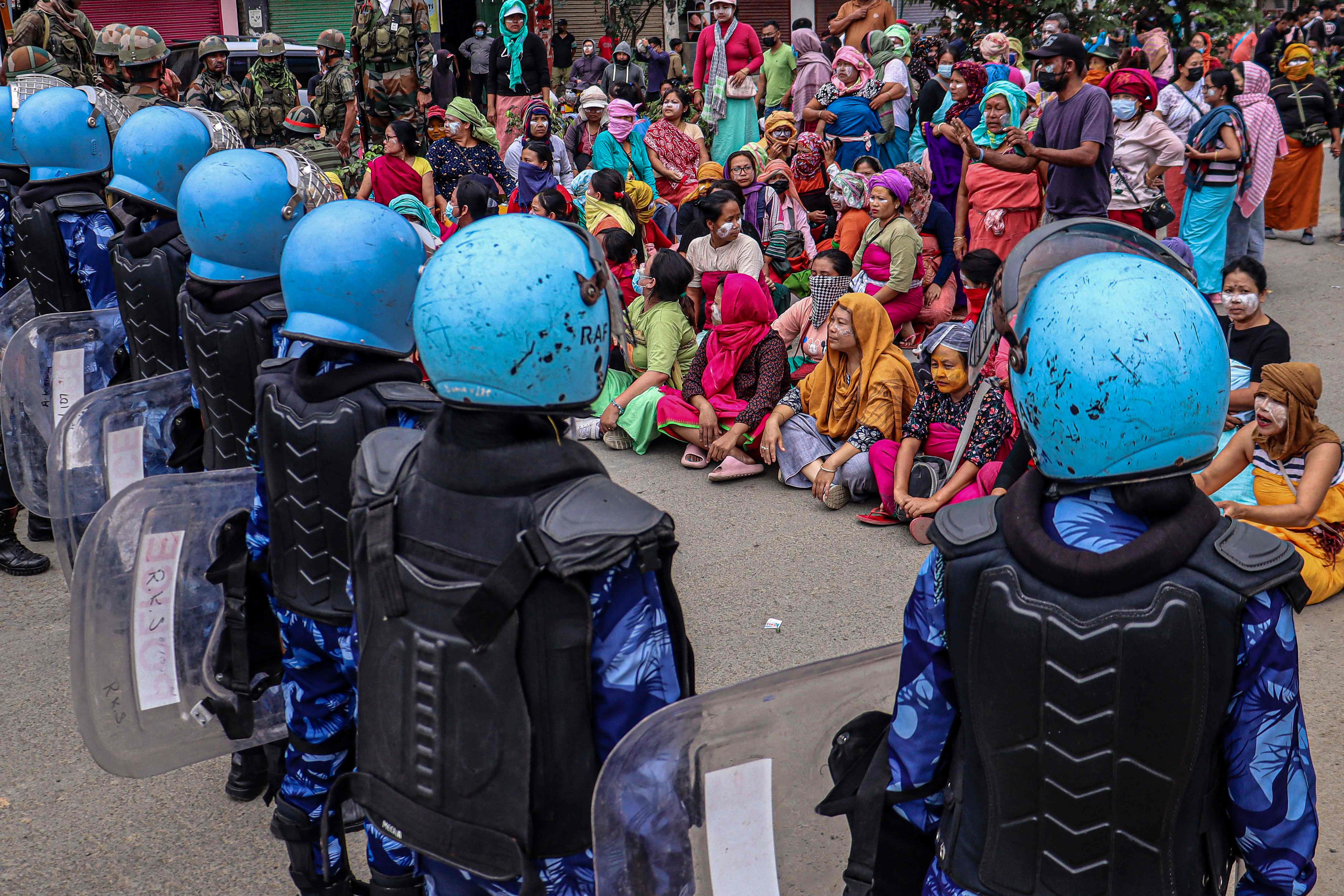 Security personnel stand guard as demonstrators protest against mass burial of Kuki-Zomi people killed in Manipur’s ethnic violence on 3 August