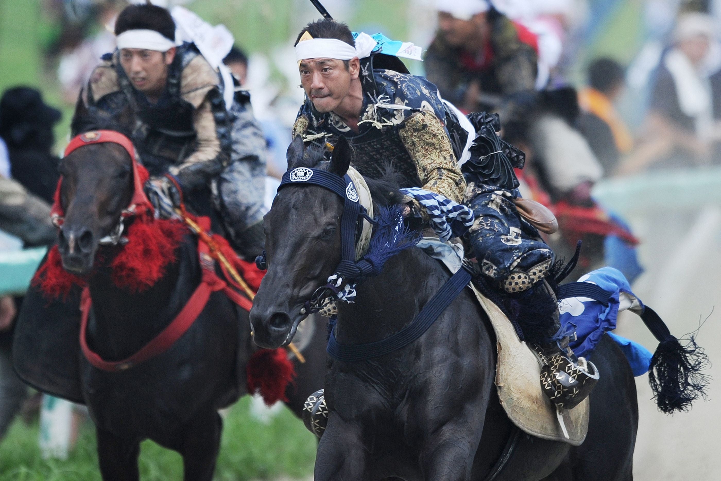 People wearing samurai armour race horses during the annual Soma Nomaoi Festival in Minamisoma, Fukushima prefecture on 29 July 2012