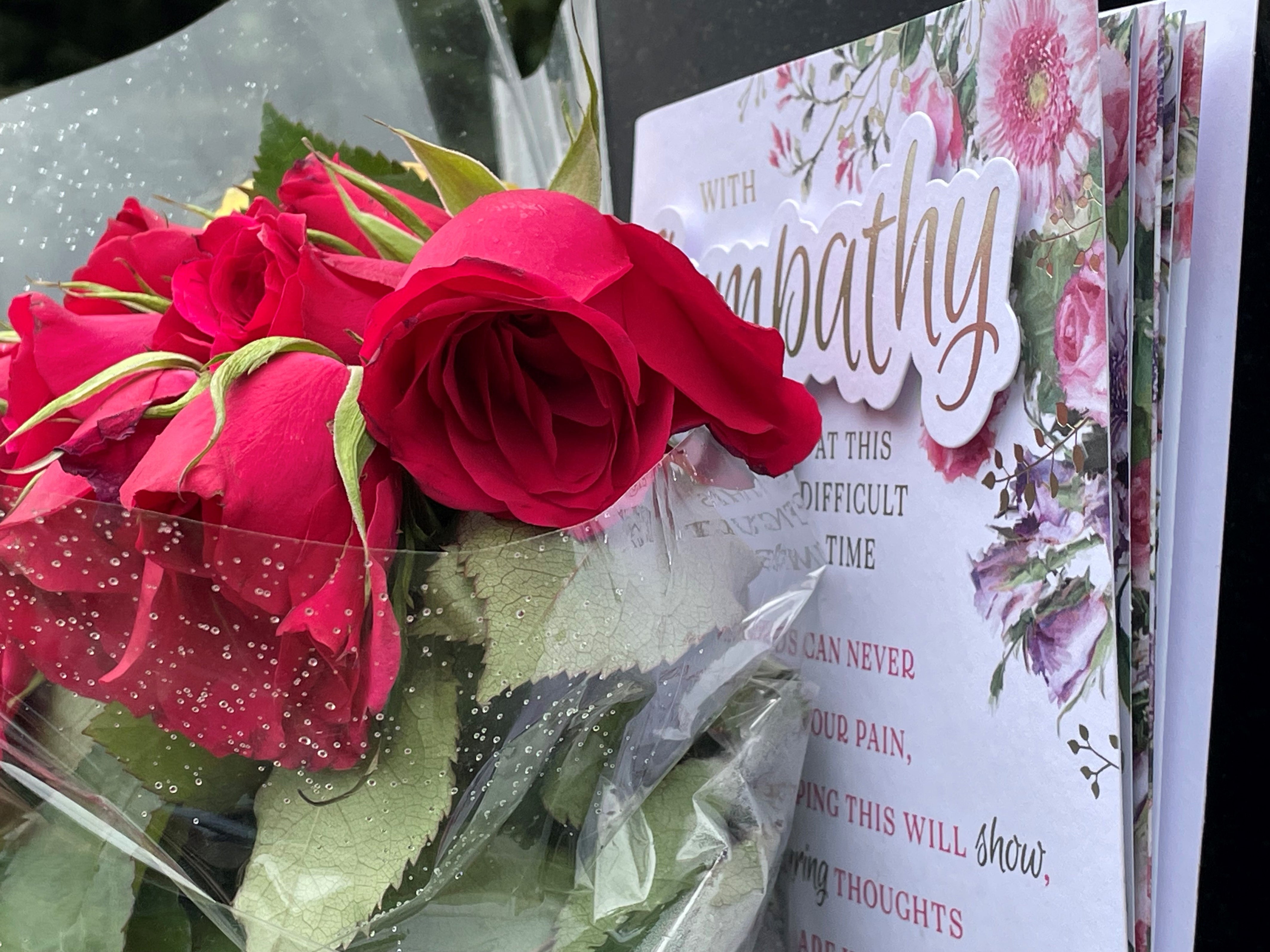Flowers and a card left on signage outside the remains of The Crooked House
