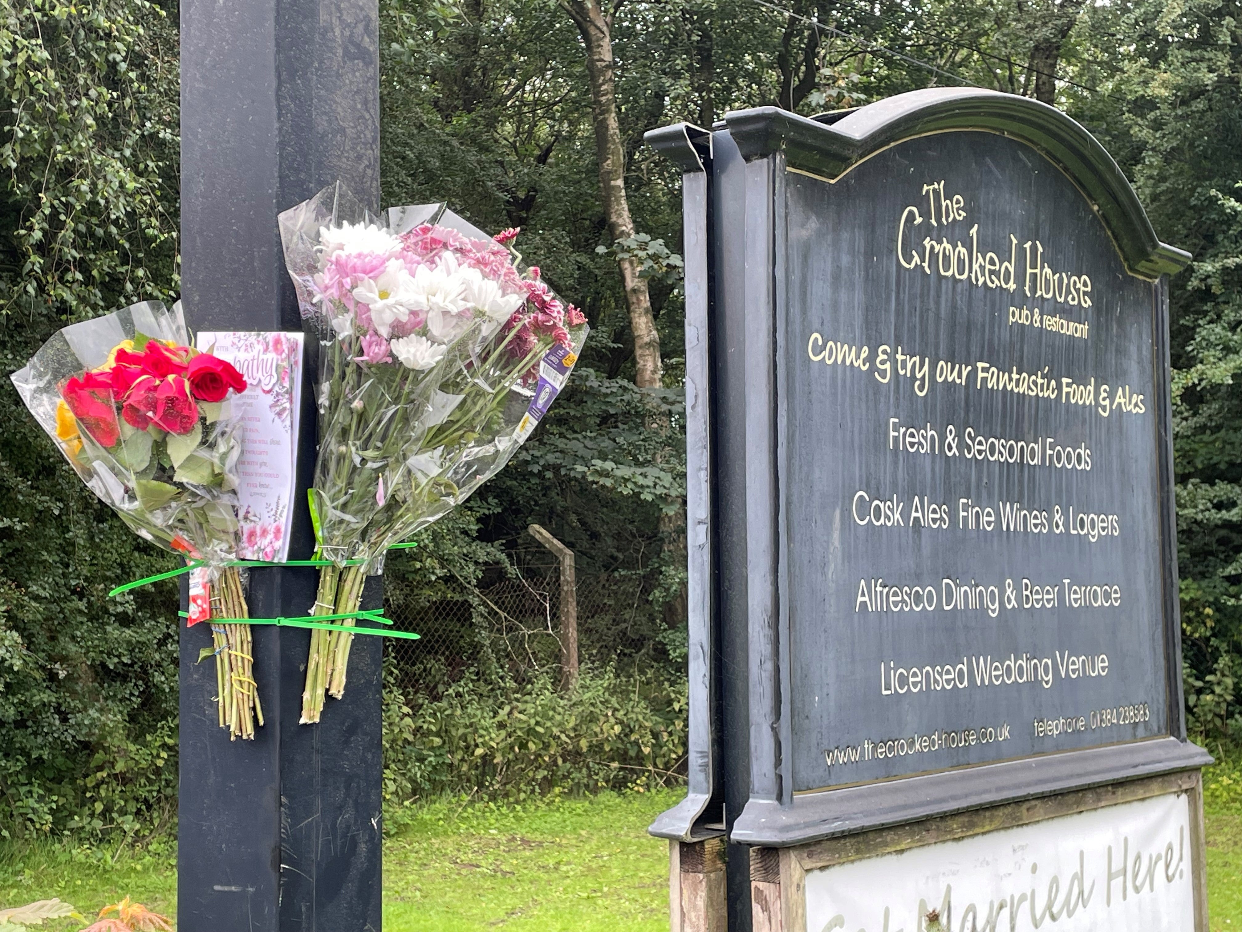 Flowers and a card left on the sign outside the remains of The Crooked House pub