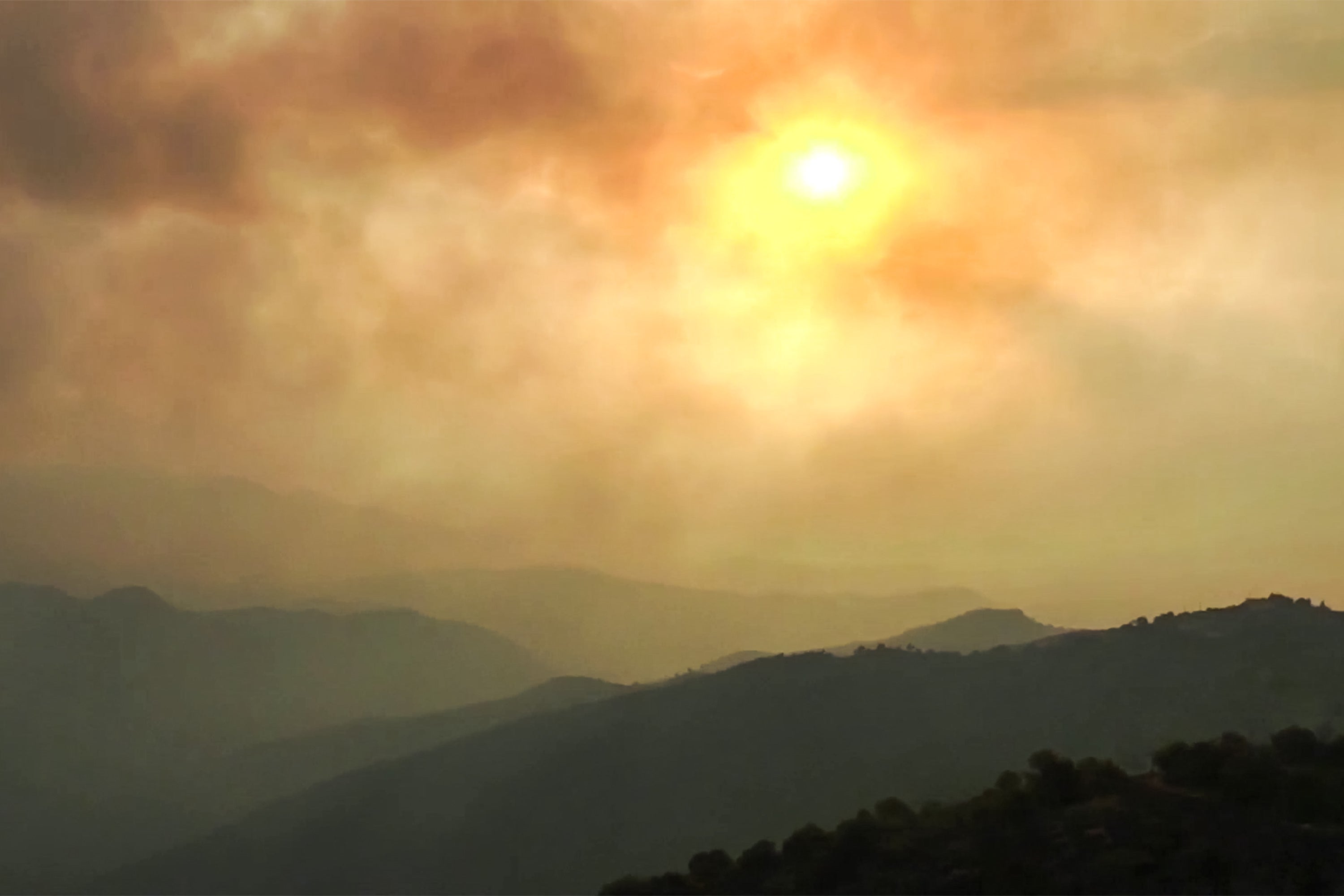 Smoke clouds cover the sky during wildfires in the forests of Bejaia in northern Algeria, 25 July