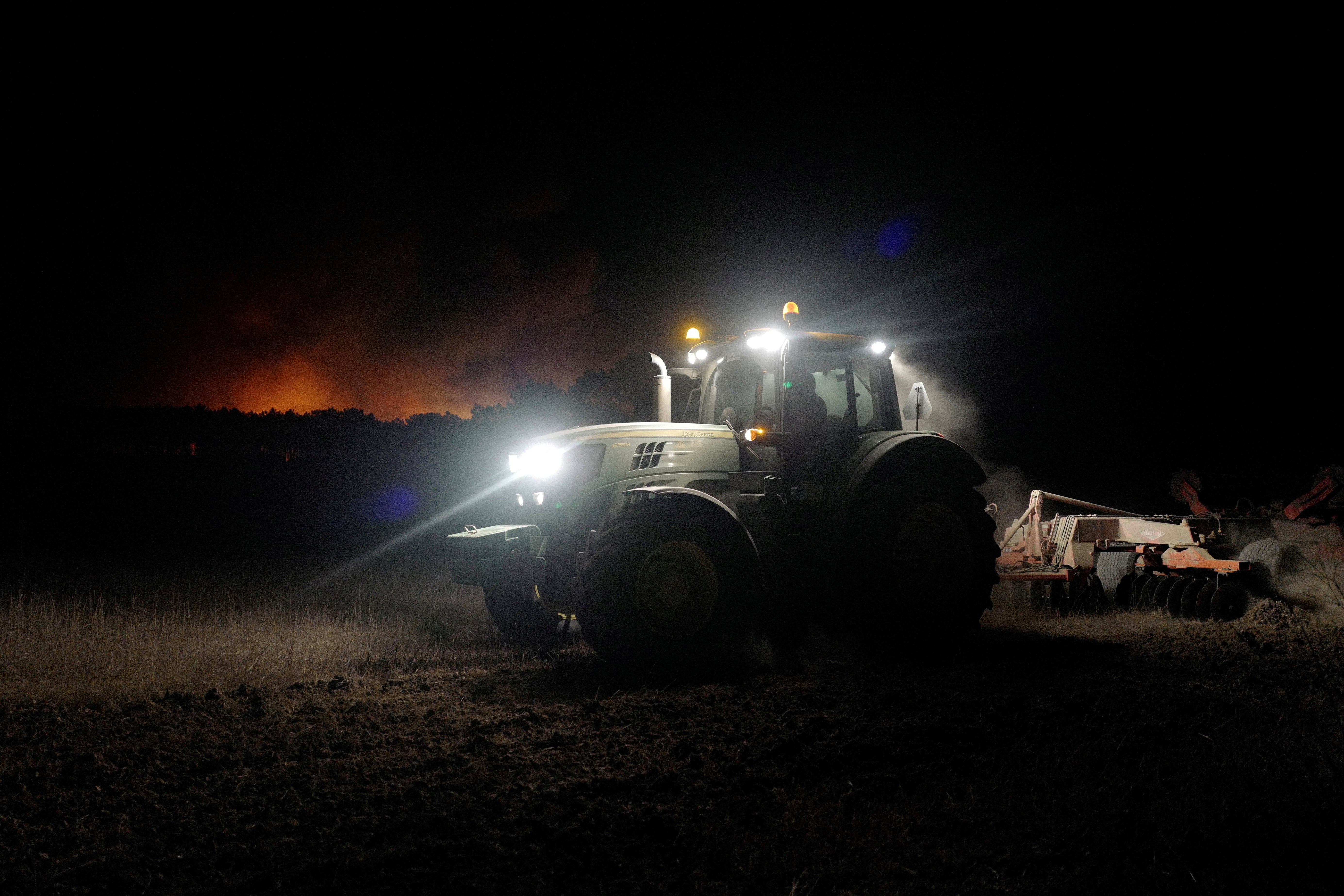 A tractor cleans up land during a wildfire in Aljezur, Portugal