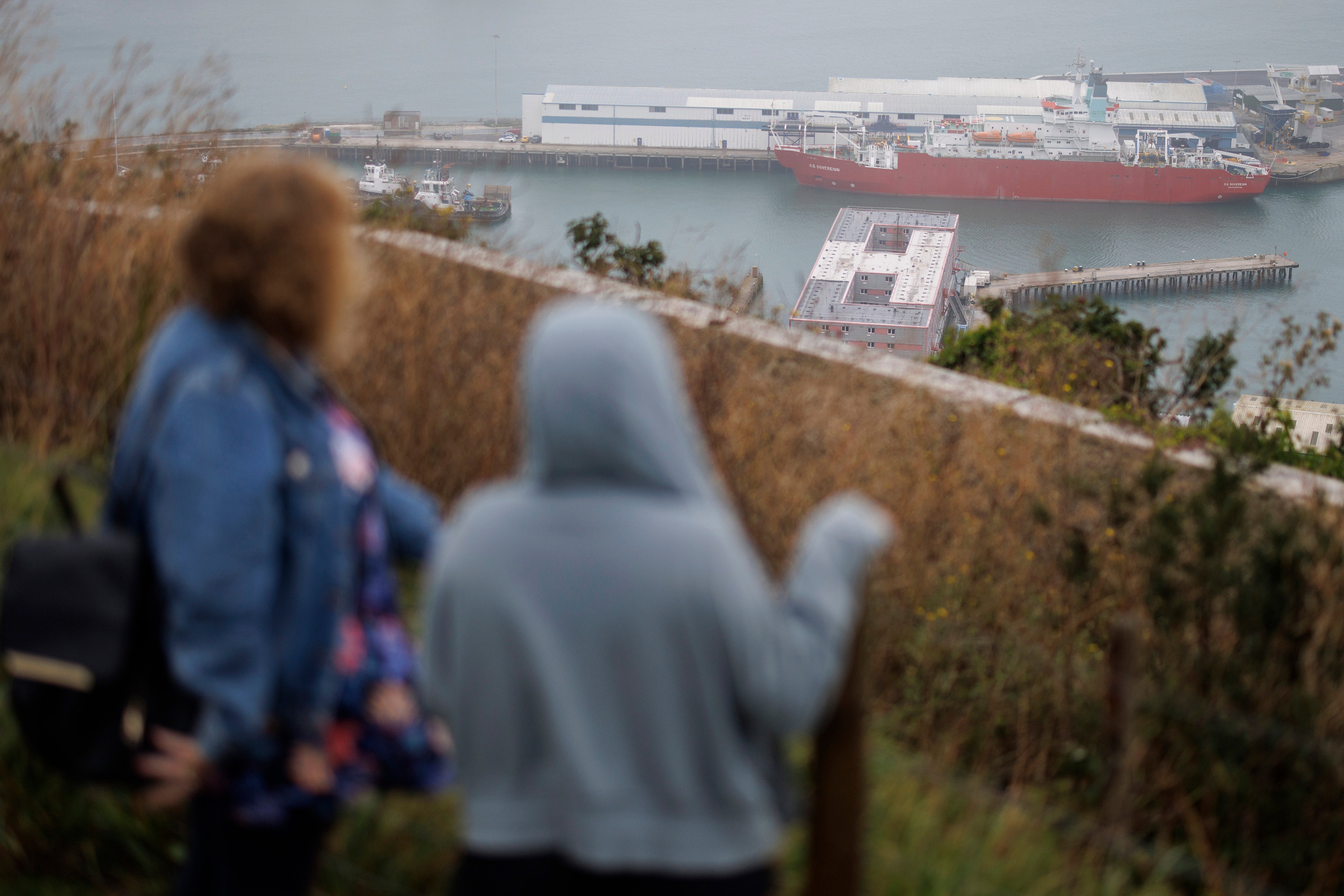 People look on at the Bibby Stockholm barge docked in Portland Port